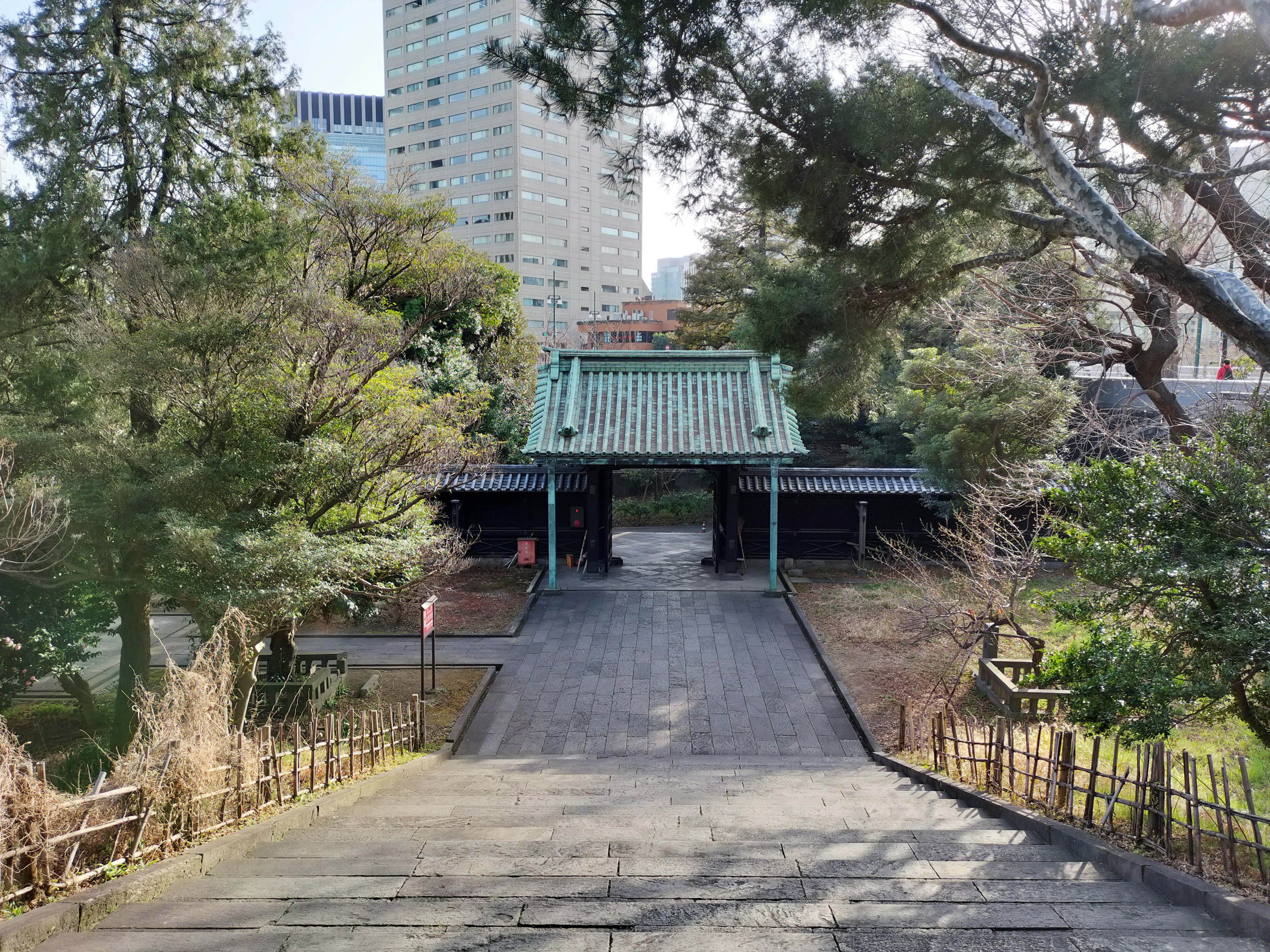 Traditional Japanese gate within a park surrounded by greenery