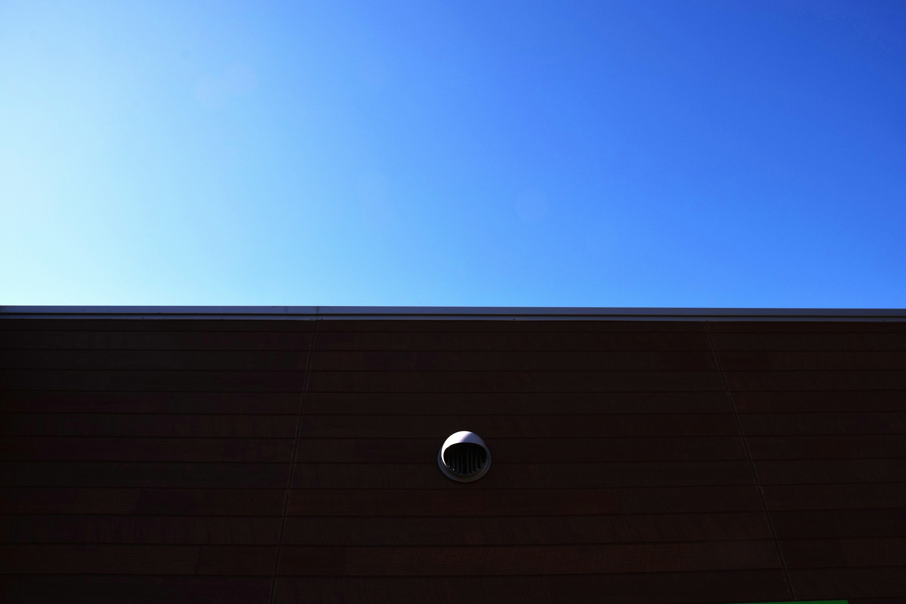 Imagen que muestra un cielo azul claro y parte de una pared de madera