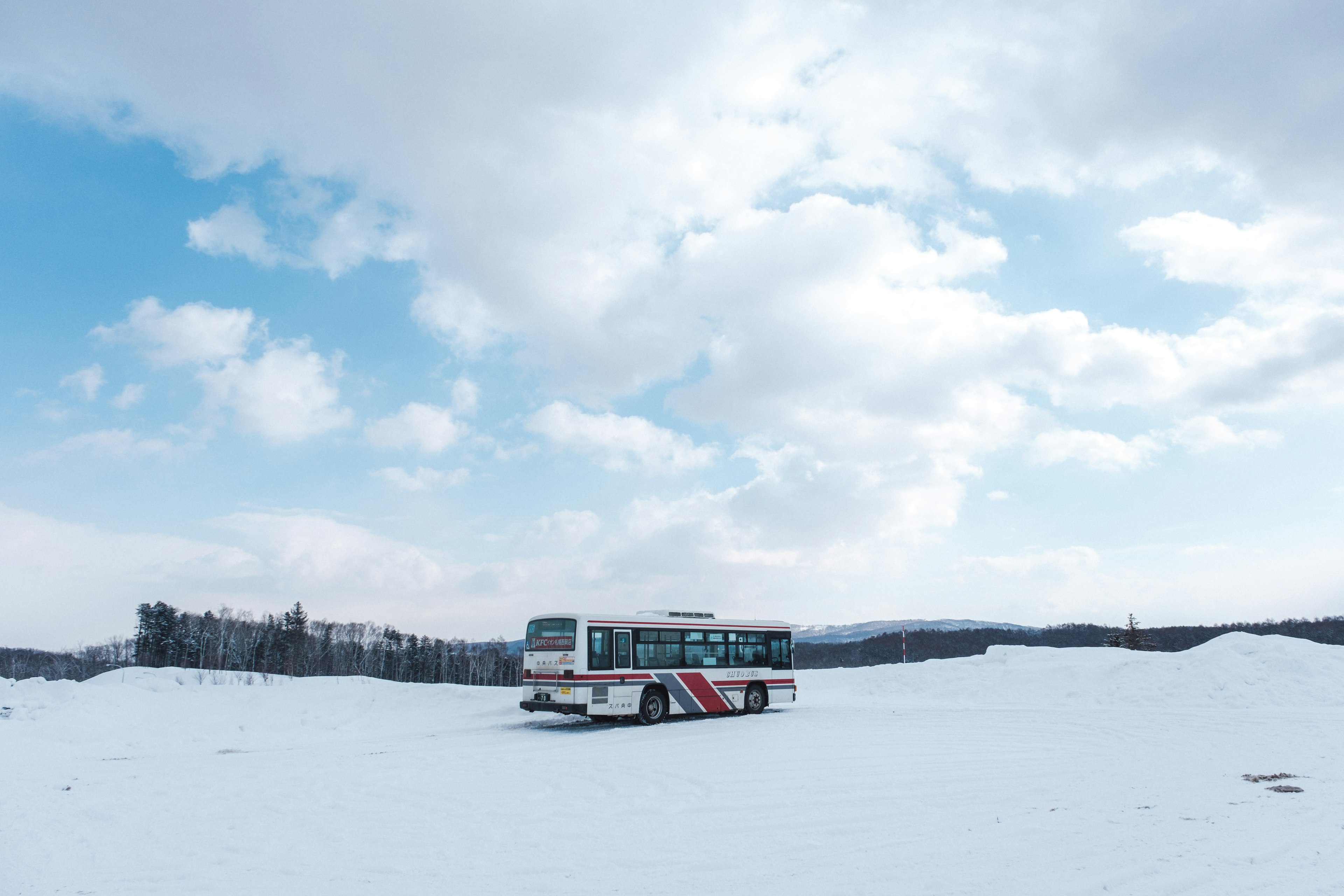 A bus parked in a snowy landscape under a cloudy sky