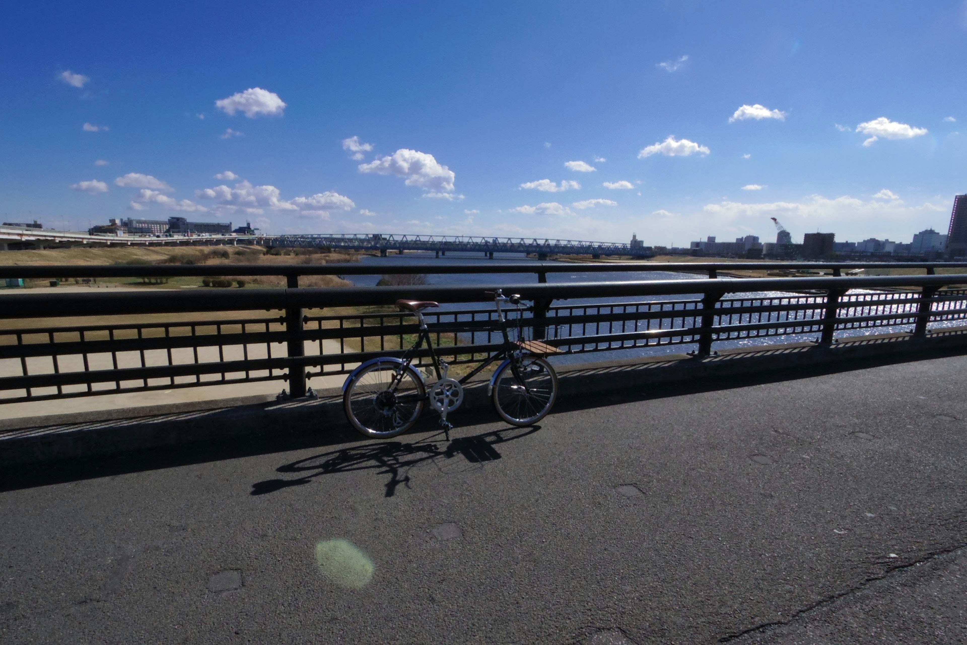 Bicycle parked beside a river under a blue sky