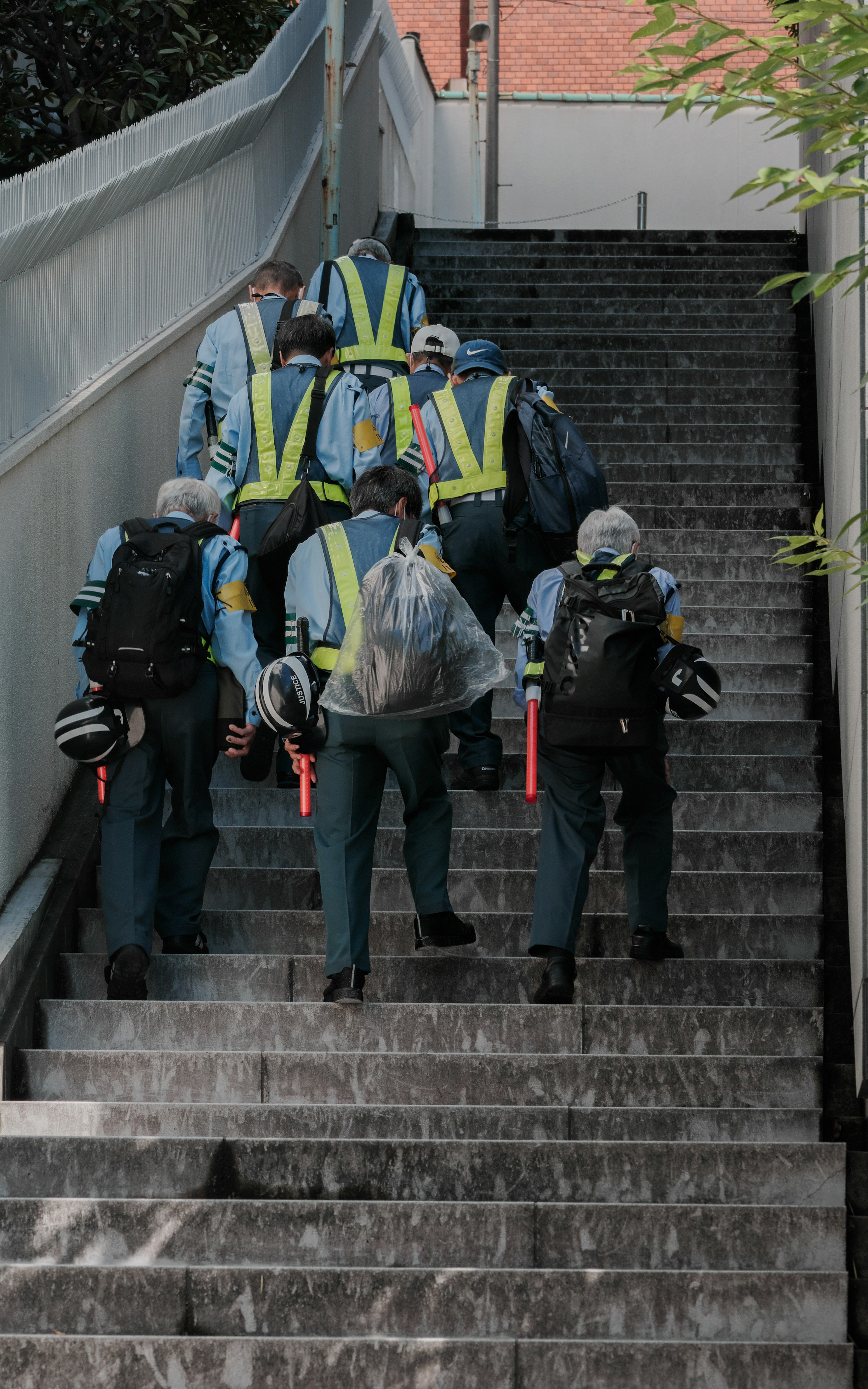 Trabajadores subiendo escaleras con chalecos reflectantes amarillos