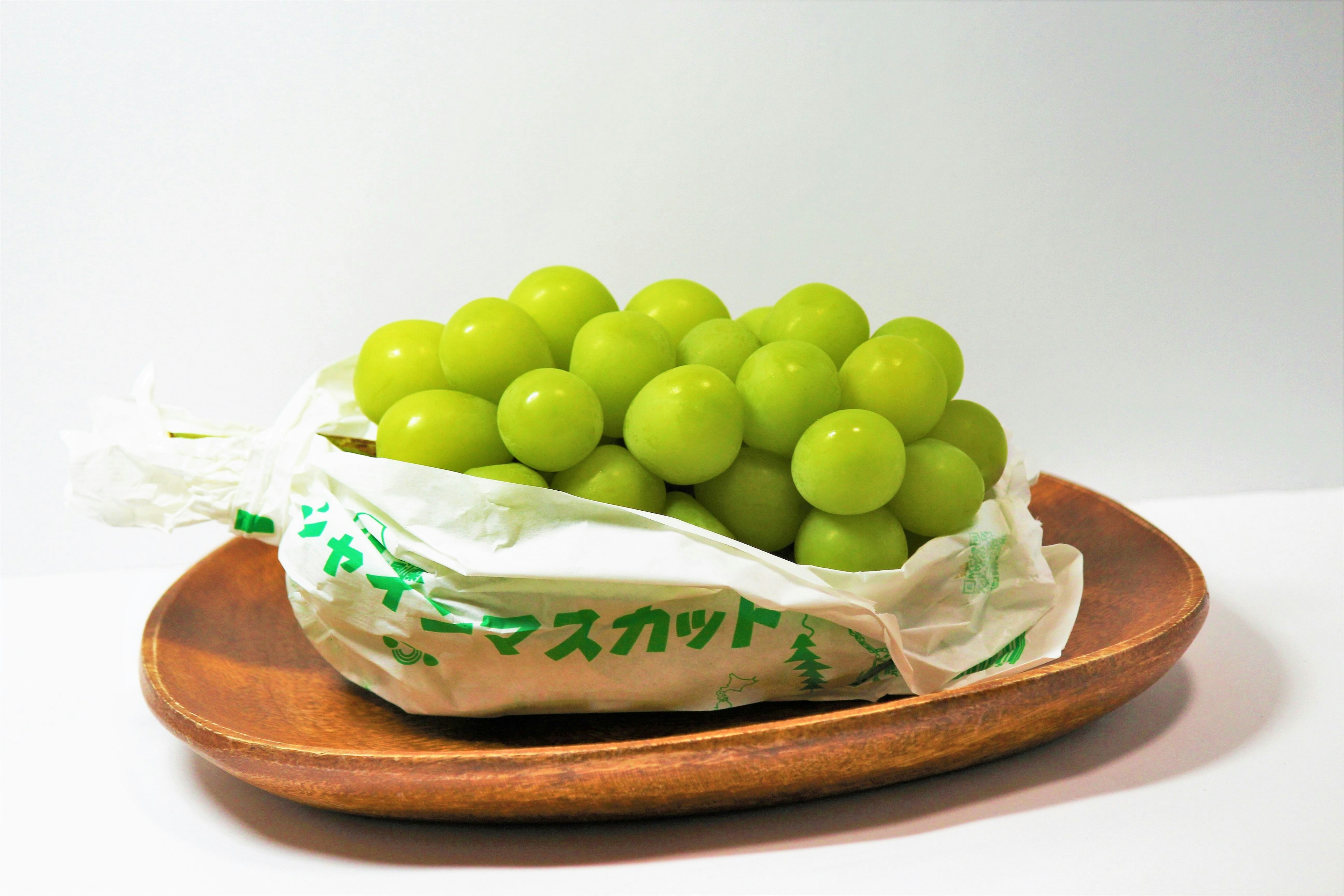 Green grapes in a bag placed on a wooden plate