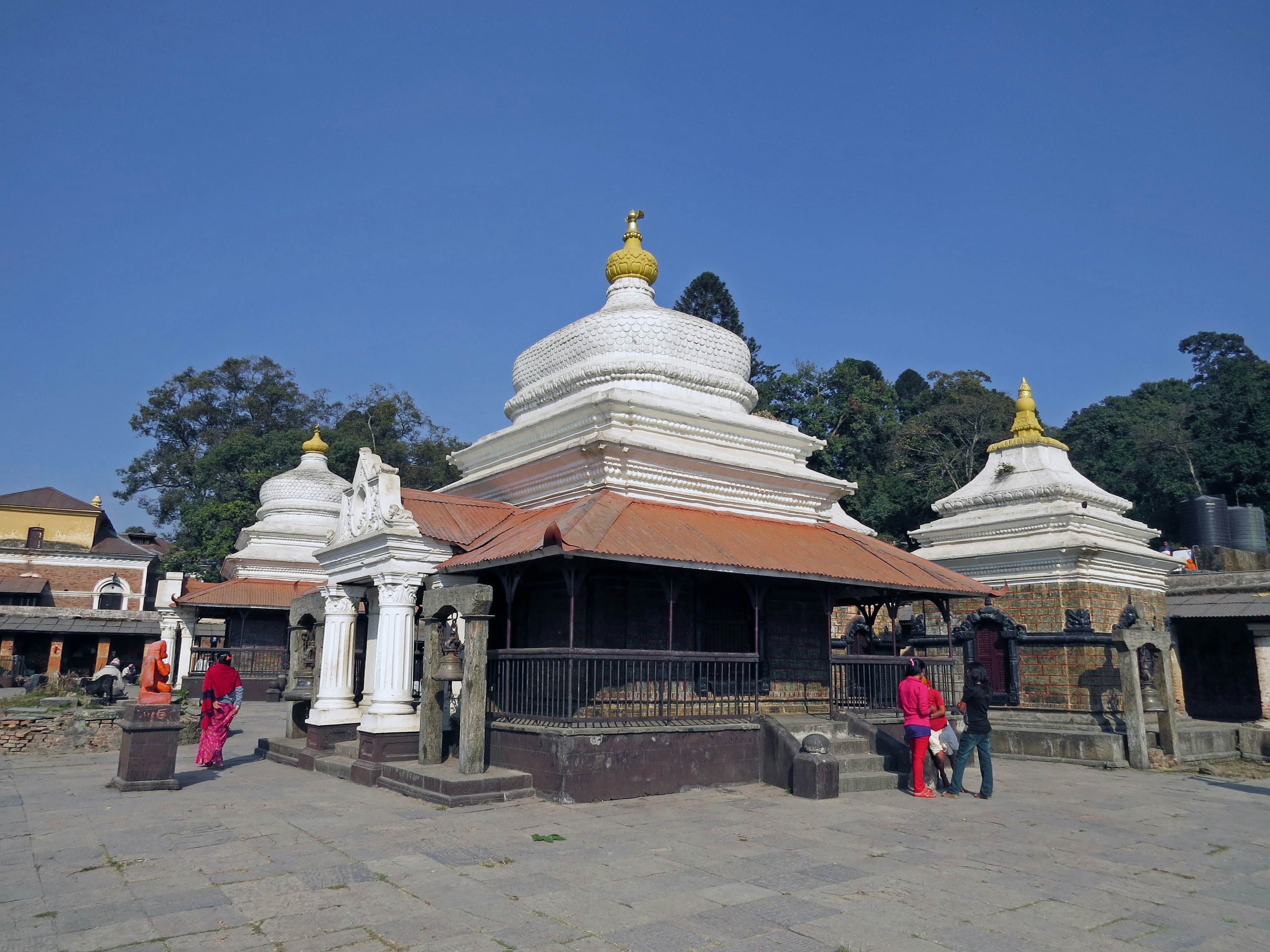 White temple complex surrounded by green hills featuring golden spires