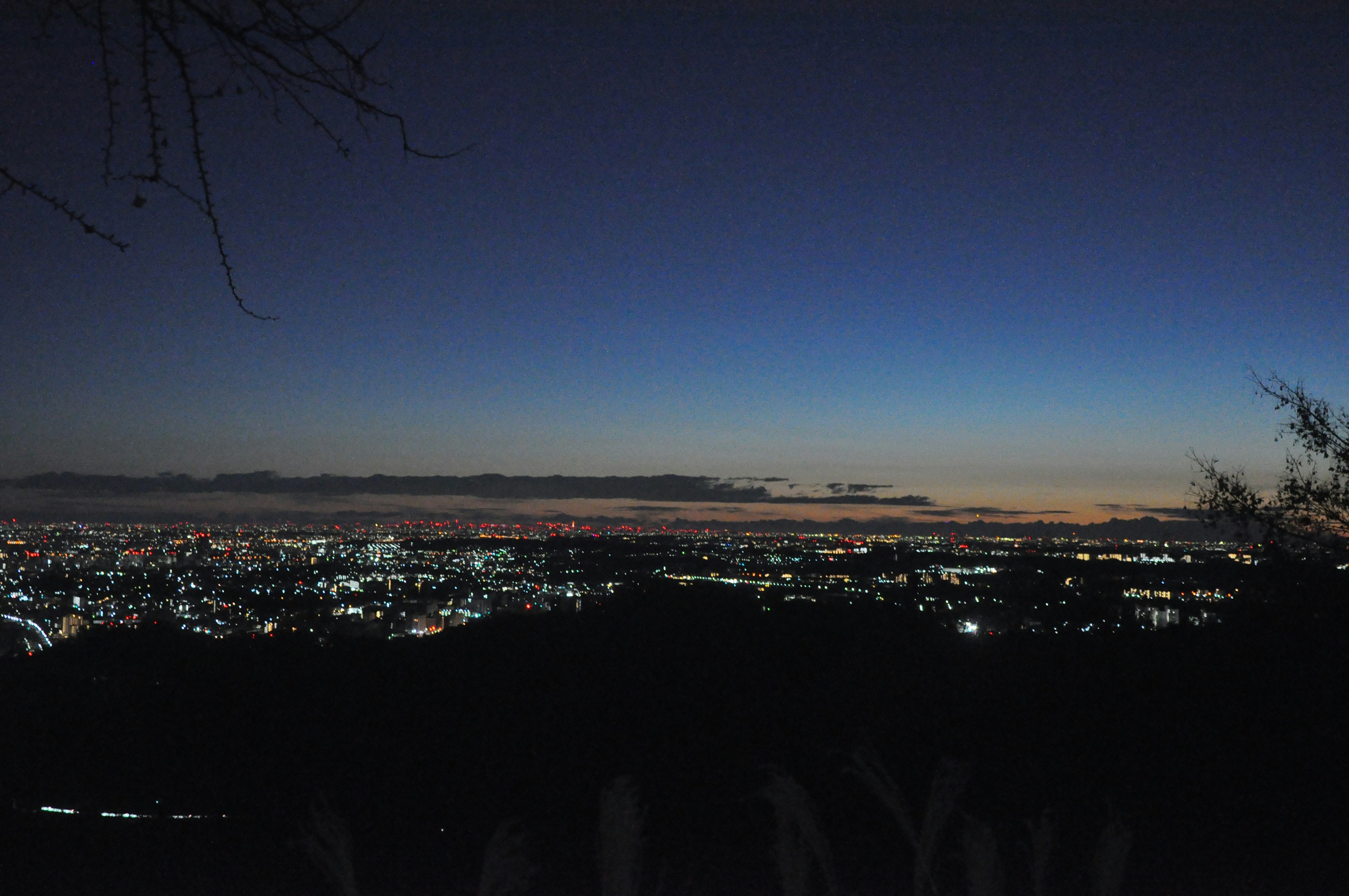 Panoramablick auf eine Stadt bei Nacht mit einem Farbverlauf von Blau zu Orange und verstreuten Lichtern