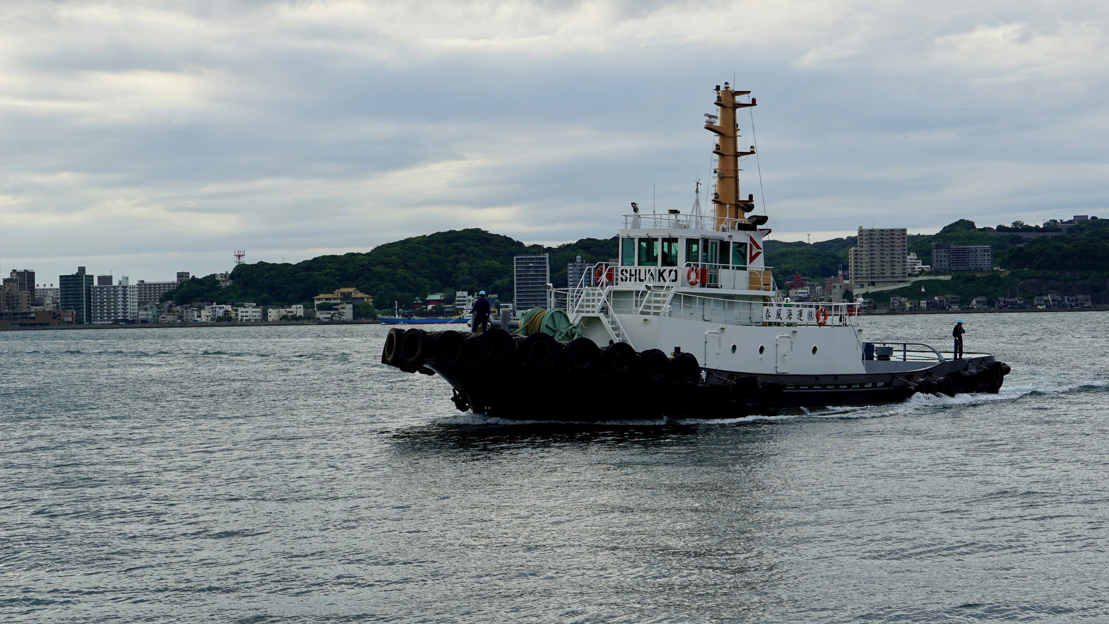 Tugboat in azione nel porto con lo skyline della città sullo sfondo