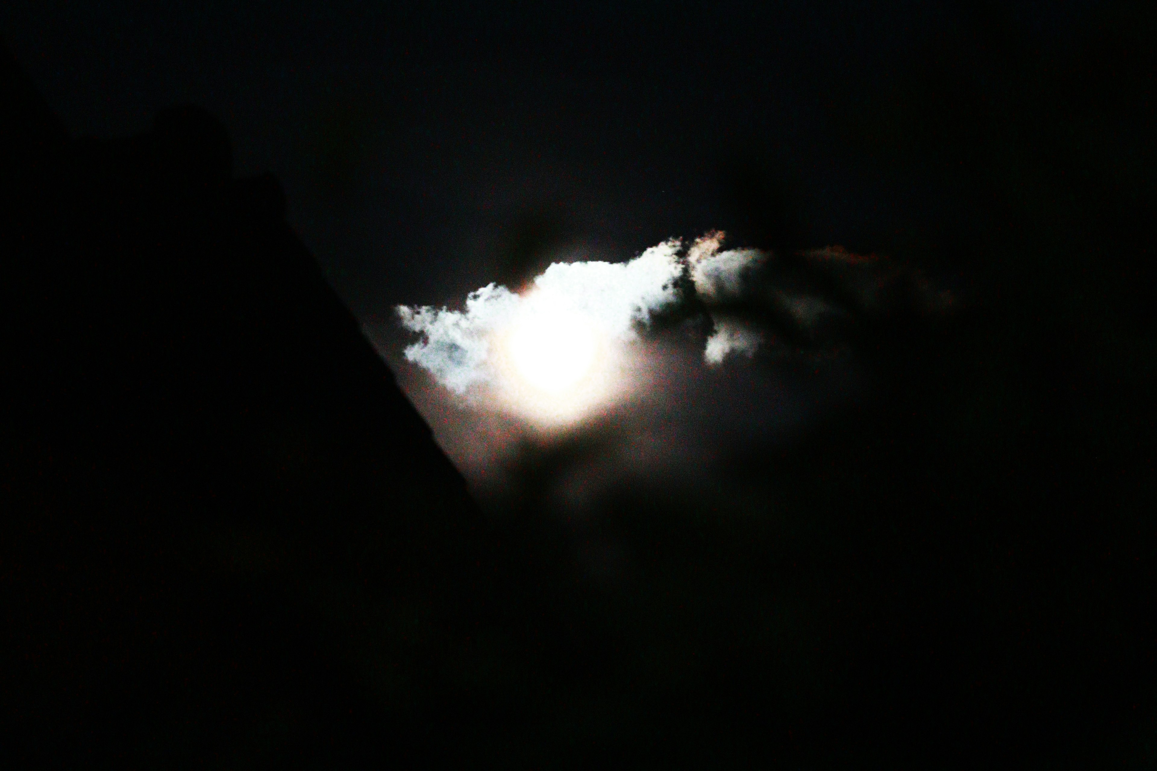 Moon partially obscured by clouds in a dark night sky