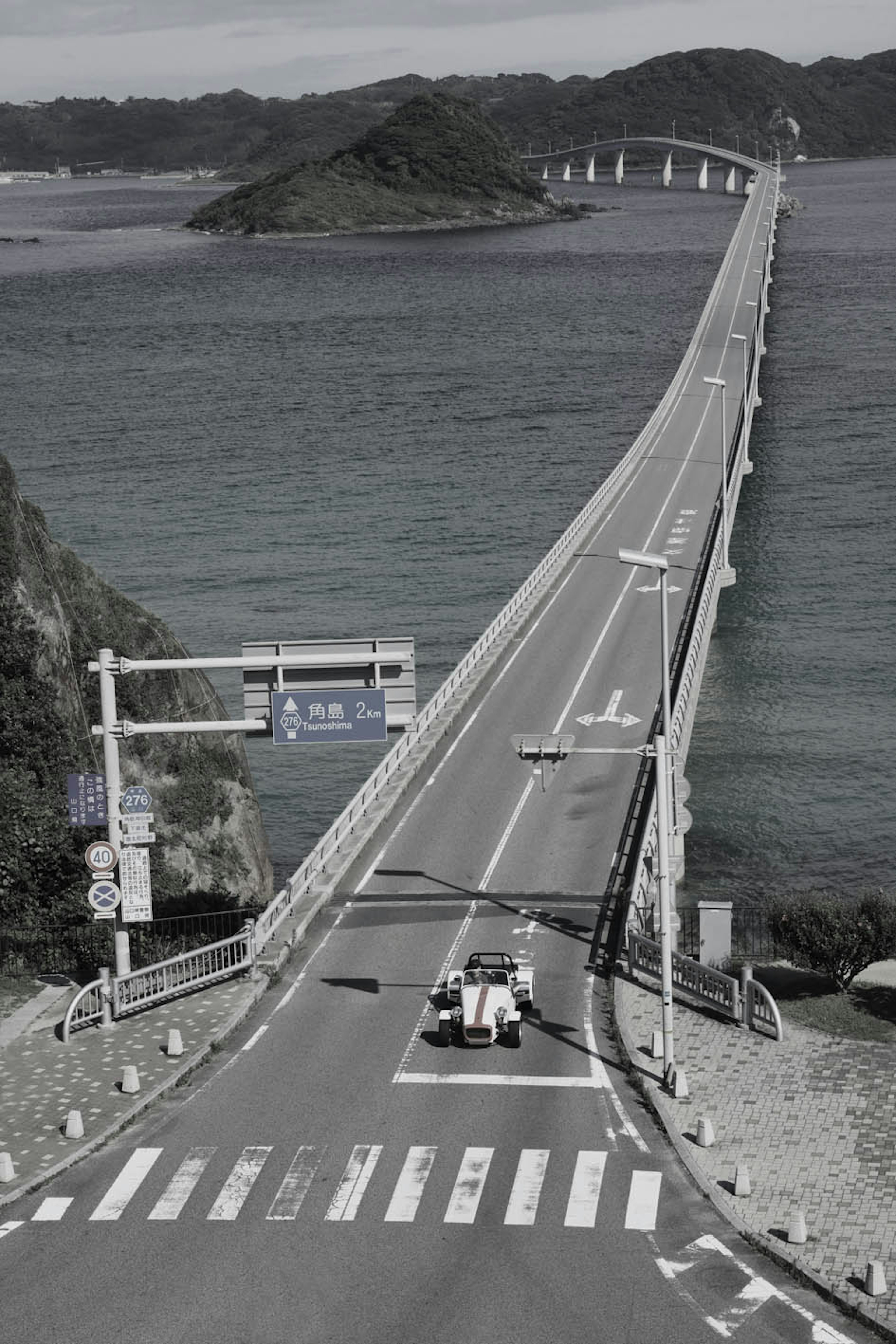 Eine lange Brücke über das Meer mit einem Fahrzeug auf der Straße