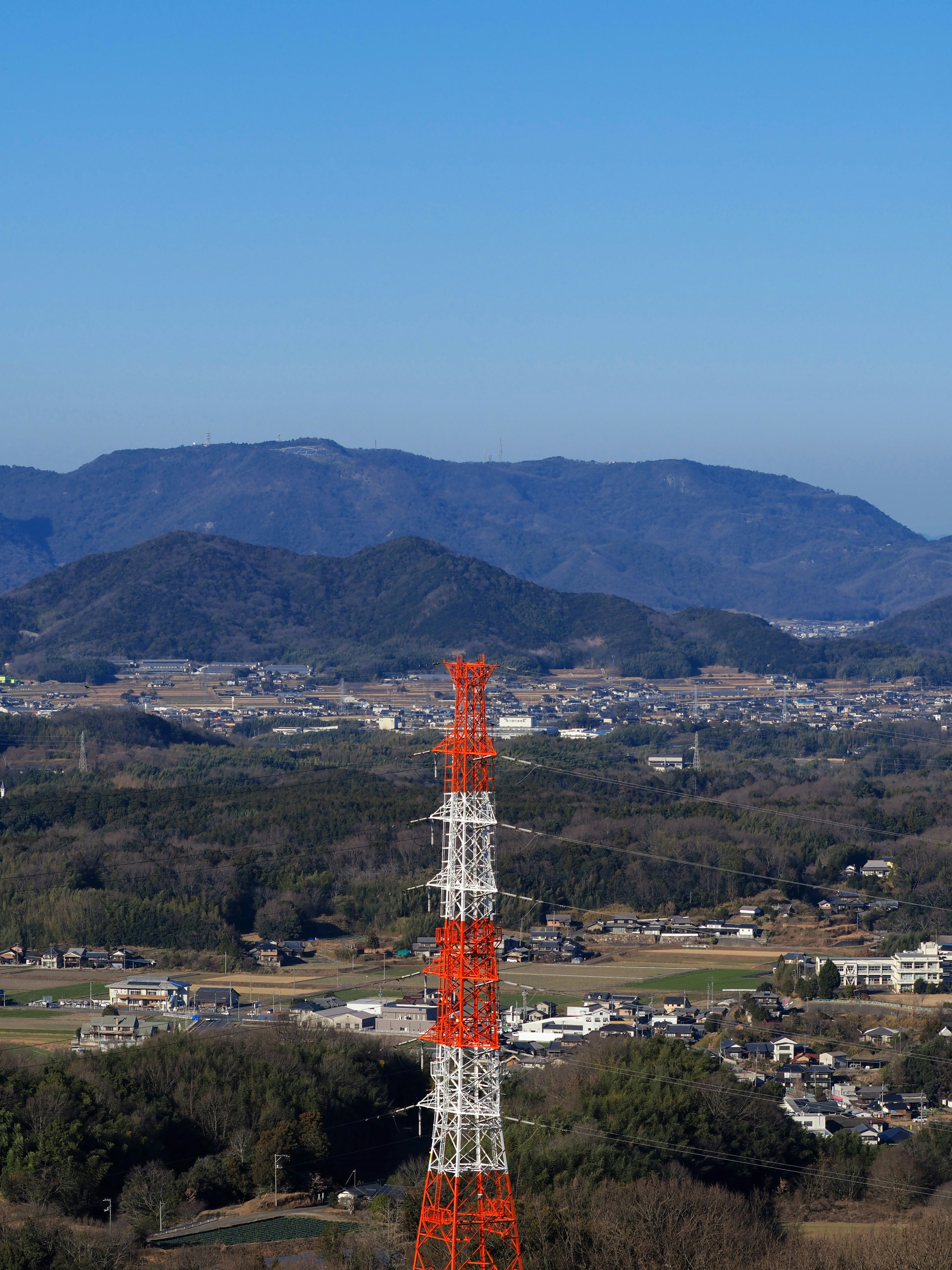 An orange and white communication tower stands against a vast landscape