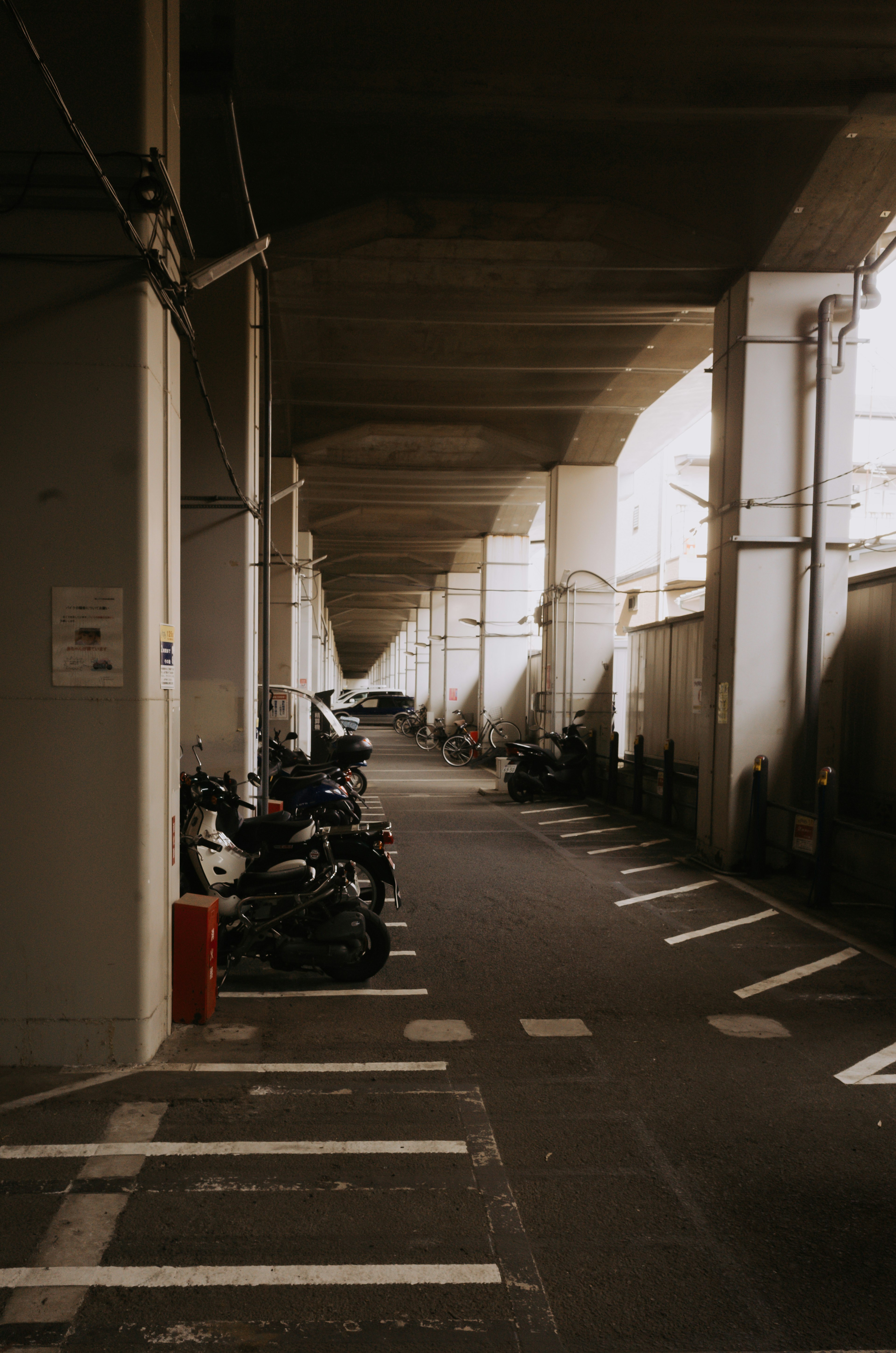 地下駐車場の通路に並ぶバイクと車の写真