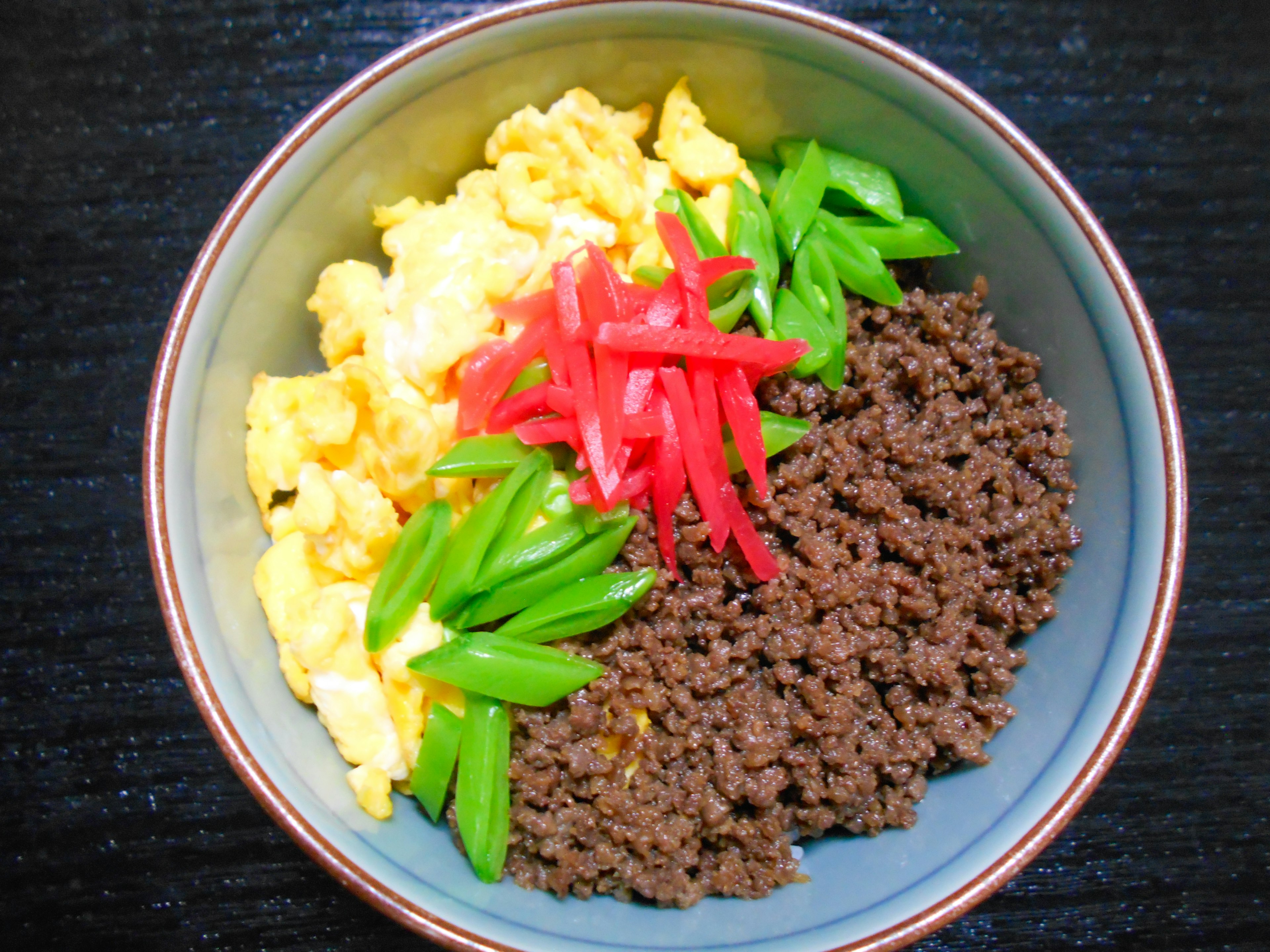 卵と牛ひき肉、ピーマン、紅生姜が盛られた丼