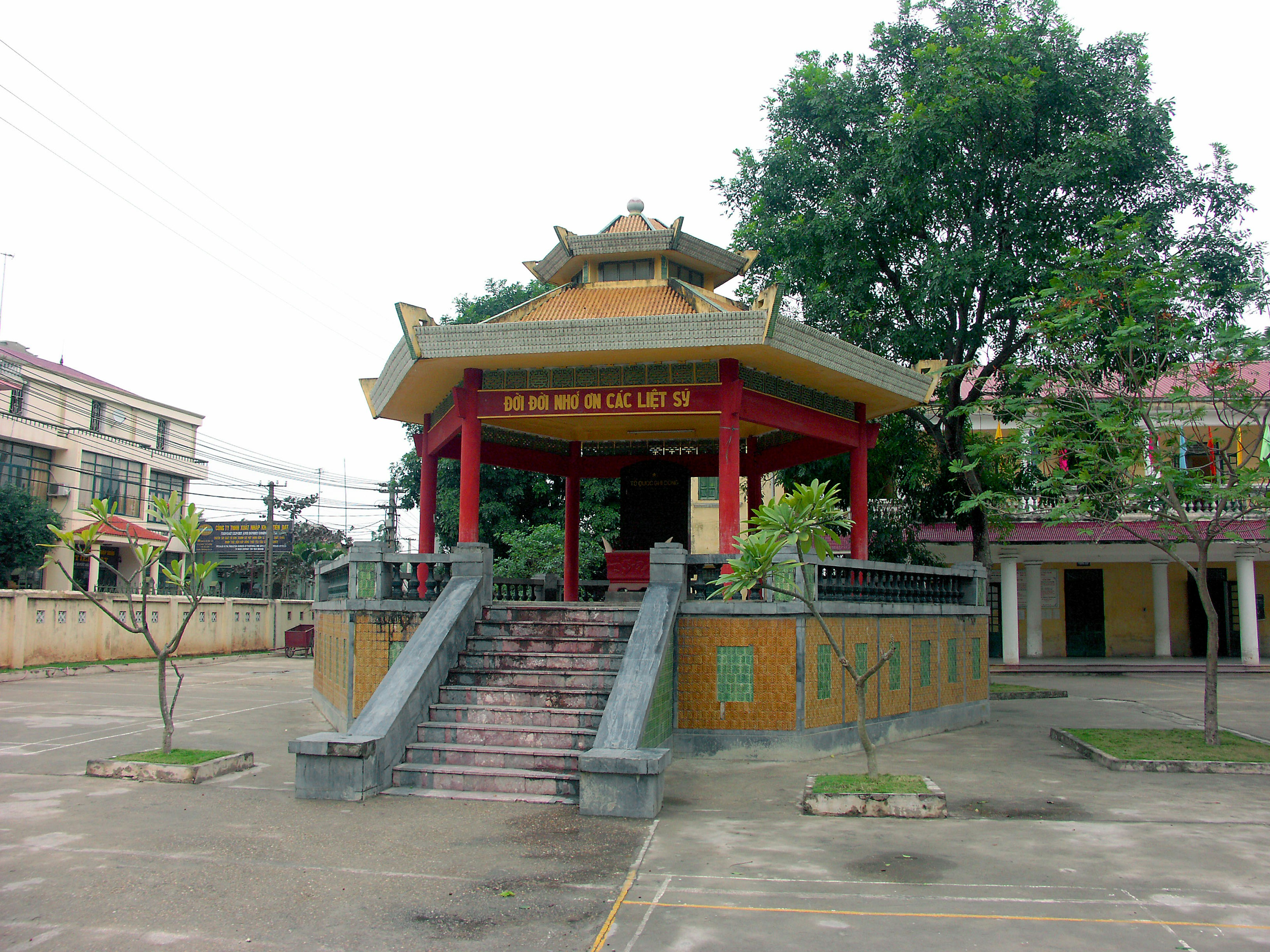 Chinese-style pavilion with a red roof standing on stairs surrounded by green trees