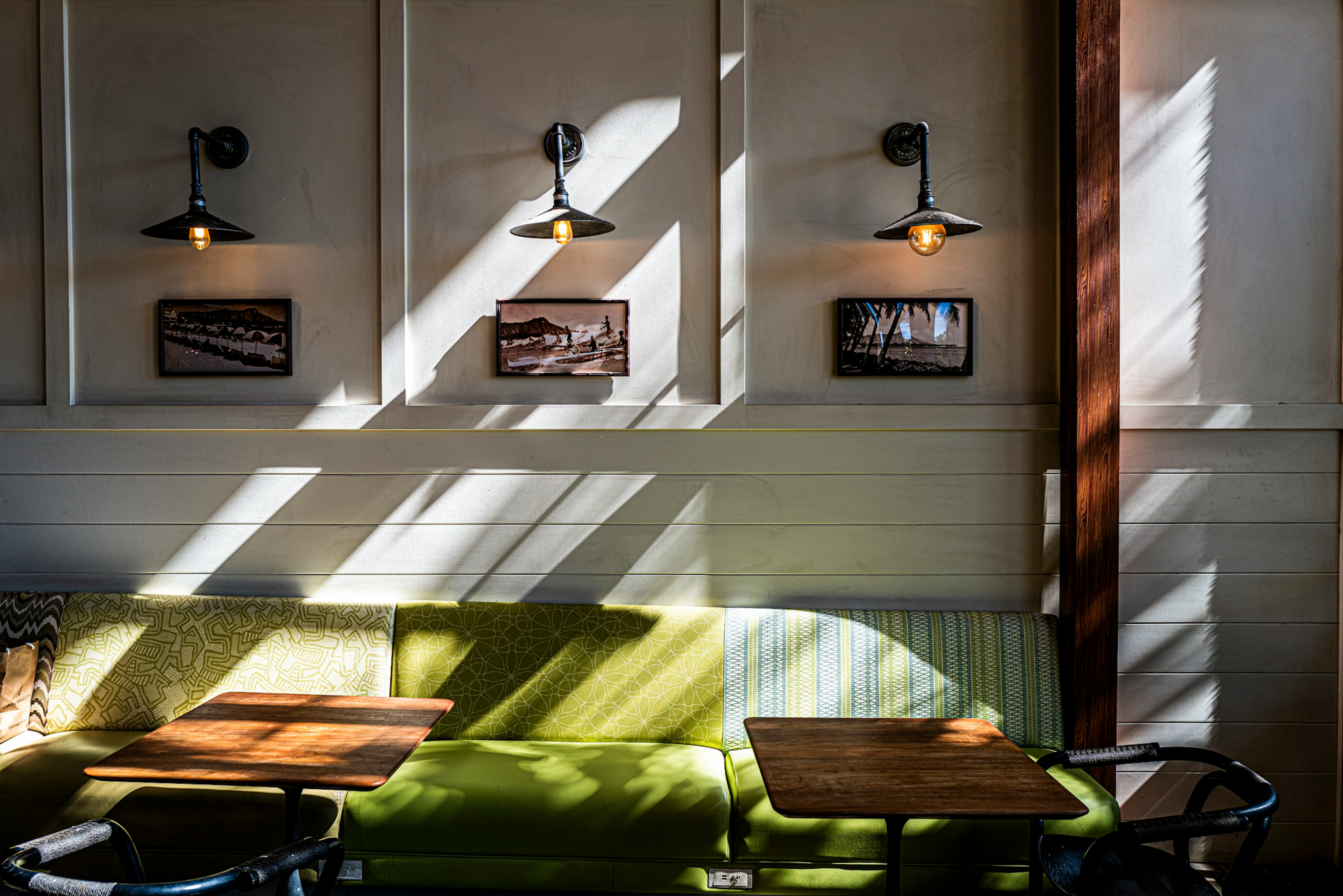 Intérieur de café lumineux avec des ombres croisées canapé vert et tables en bois