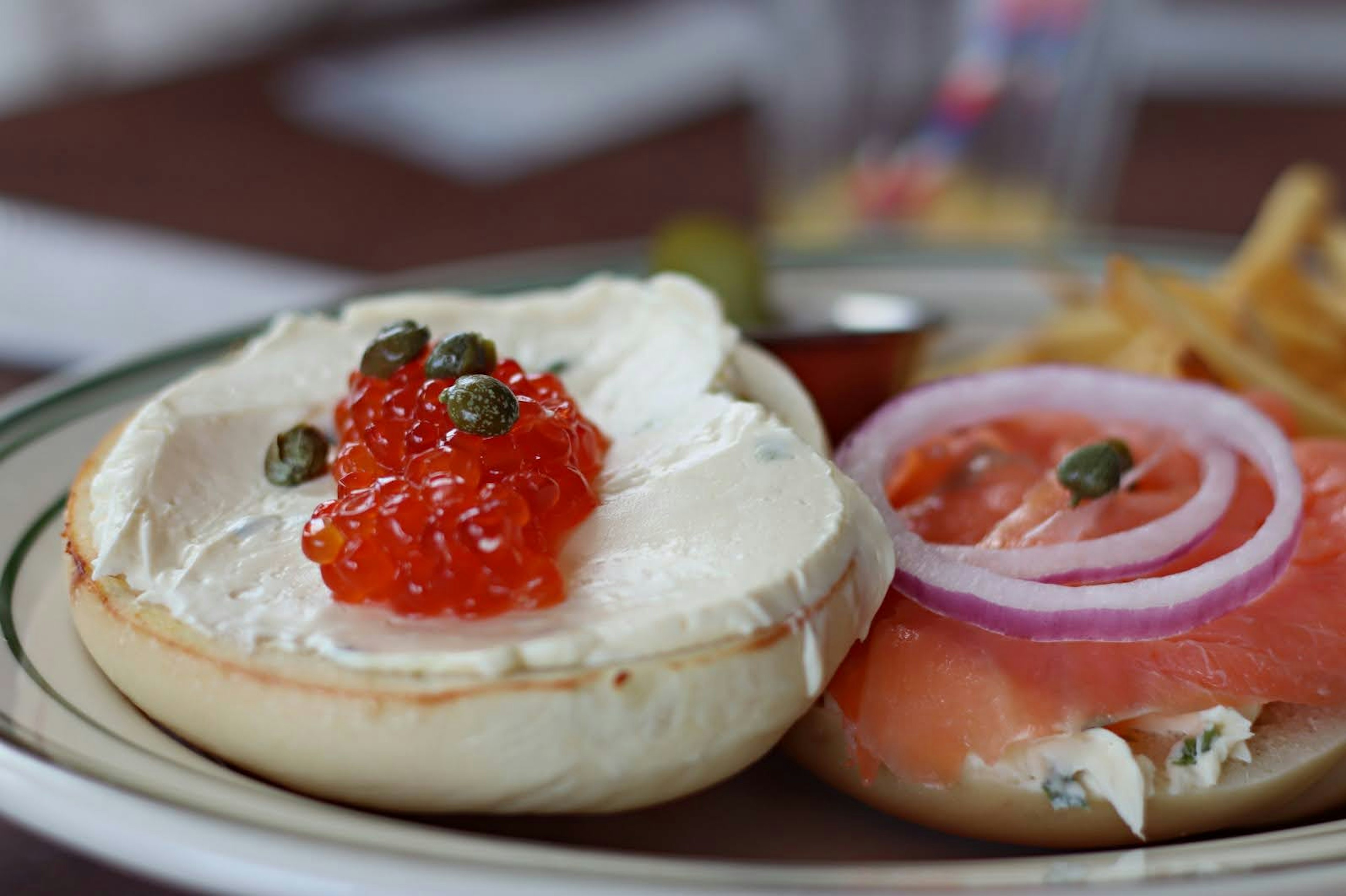 Bagel con crema di formaggio e caviale accanto a un panino con salmone affumicato