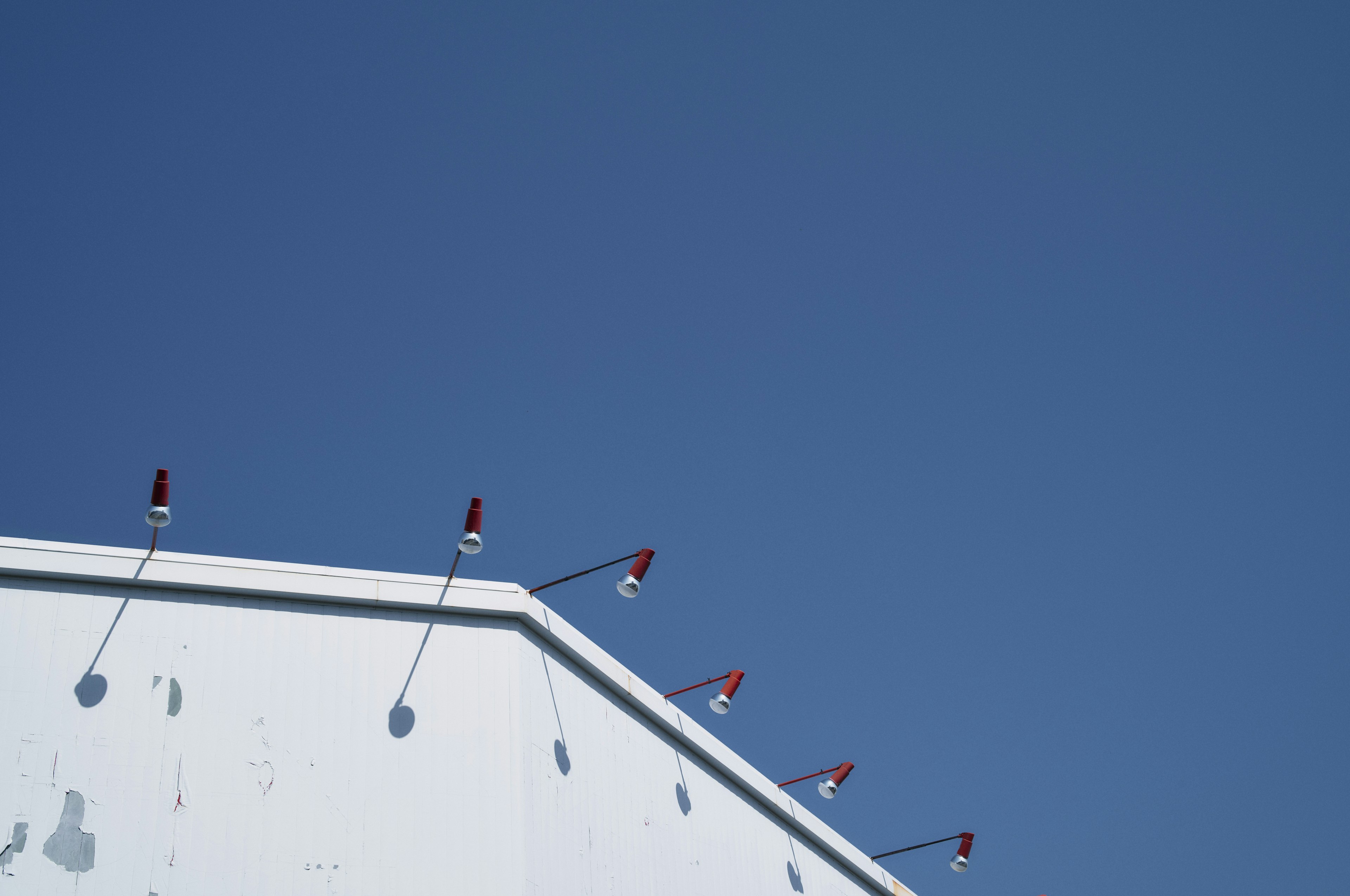 White building roof with red lamps against a blue sky