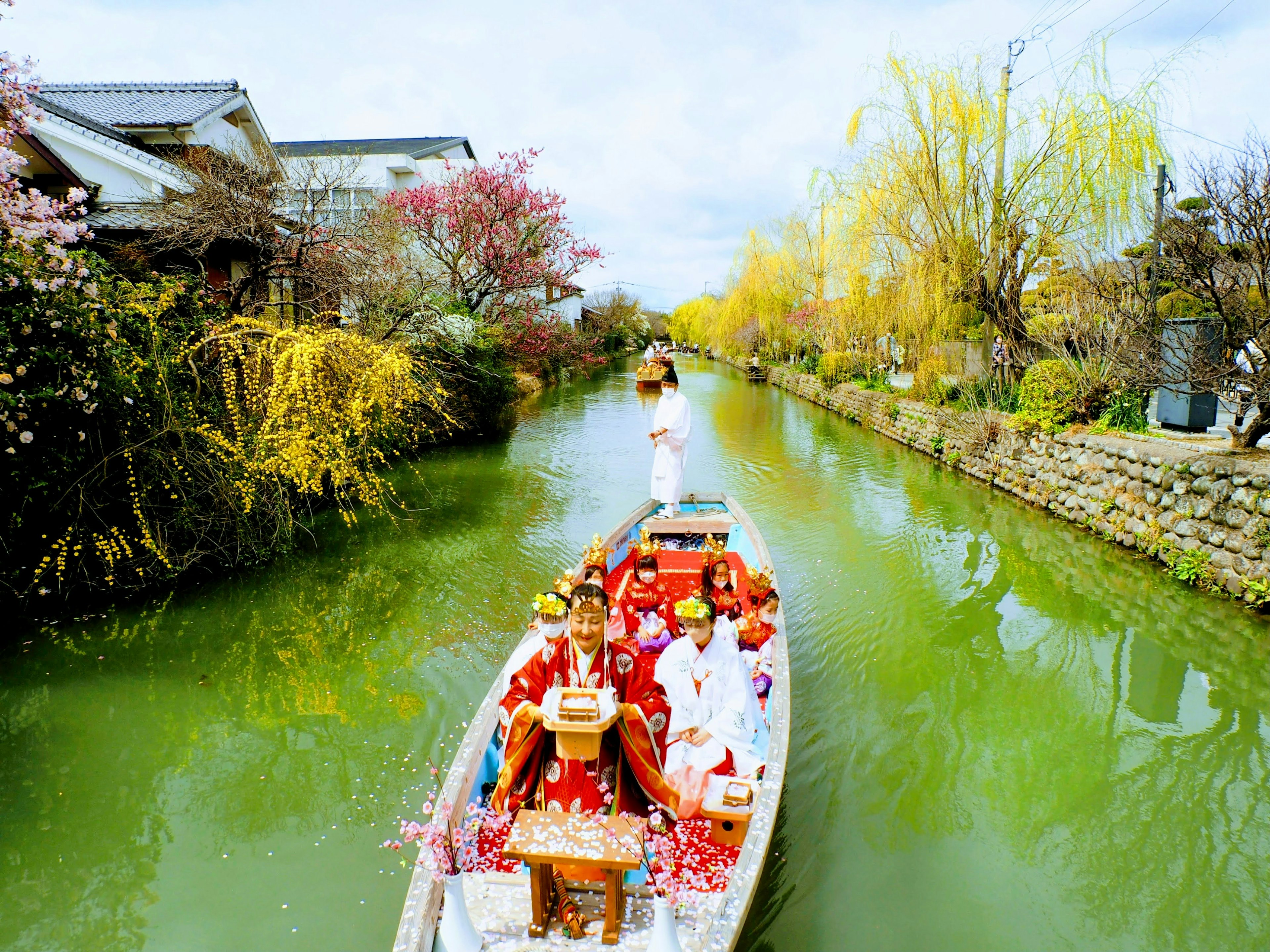 เรือประเพณีกับผู้คนในชุดกิโมโนบนแม่น้ำสีเขียวที่เงียบสงบ