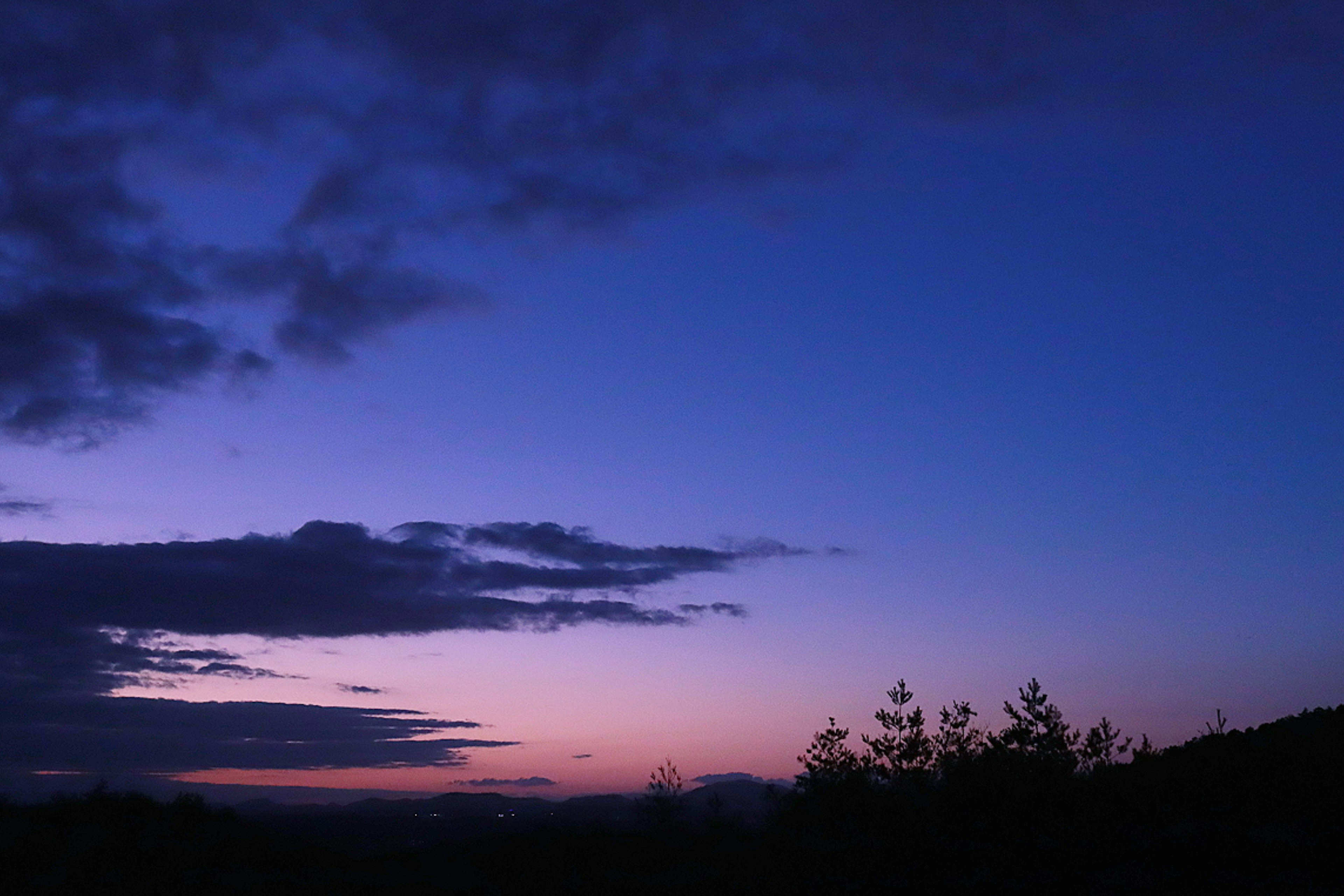 Serene twilight sky with a gradient of blue and purple hues and silhouetted clouds