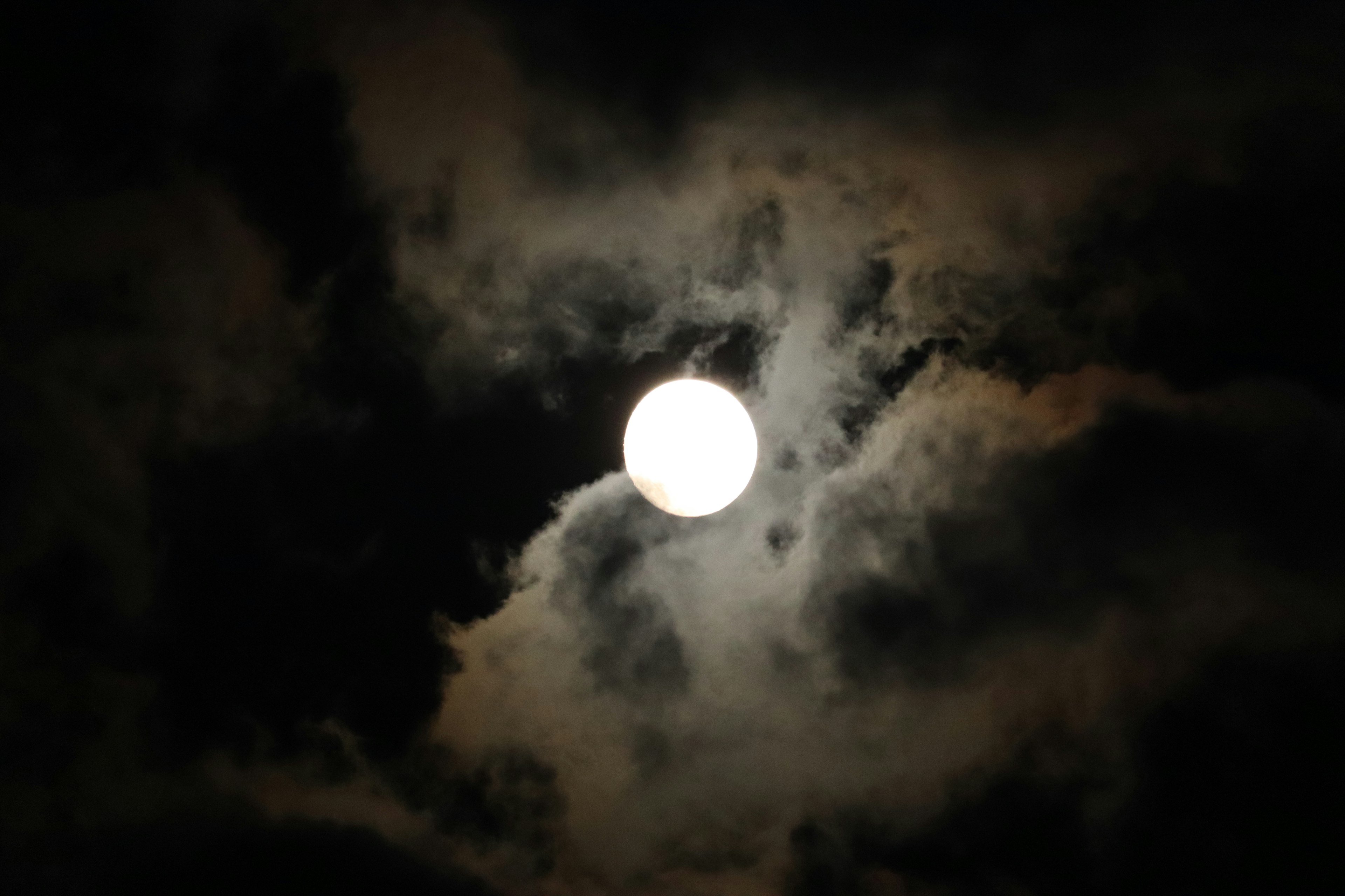 Full moon glowing amidst dark clouds