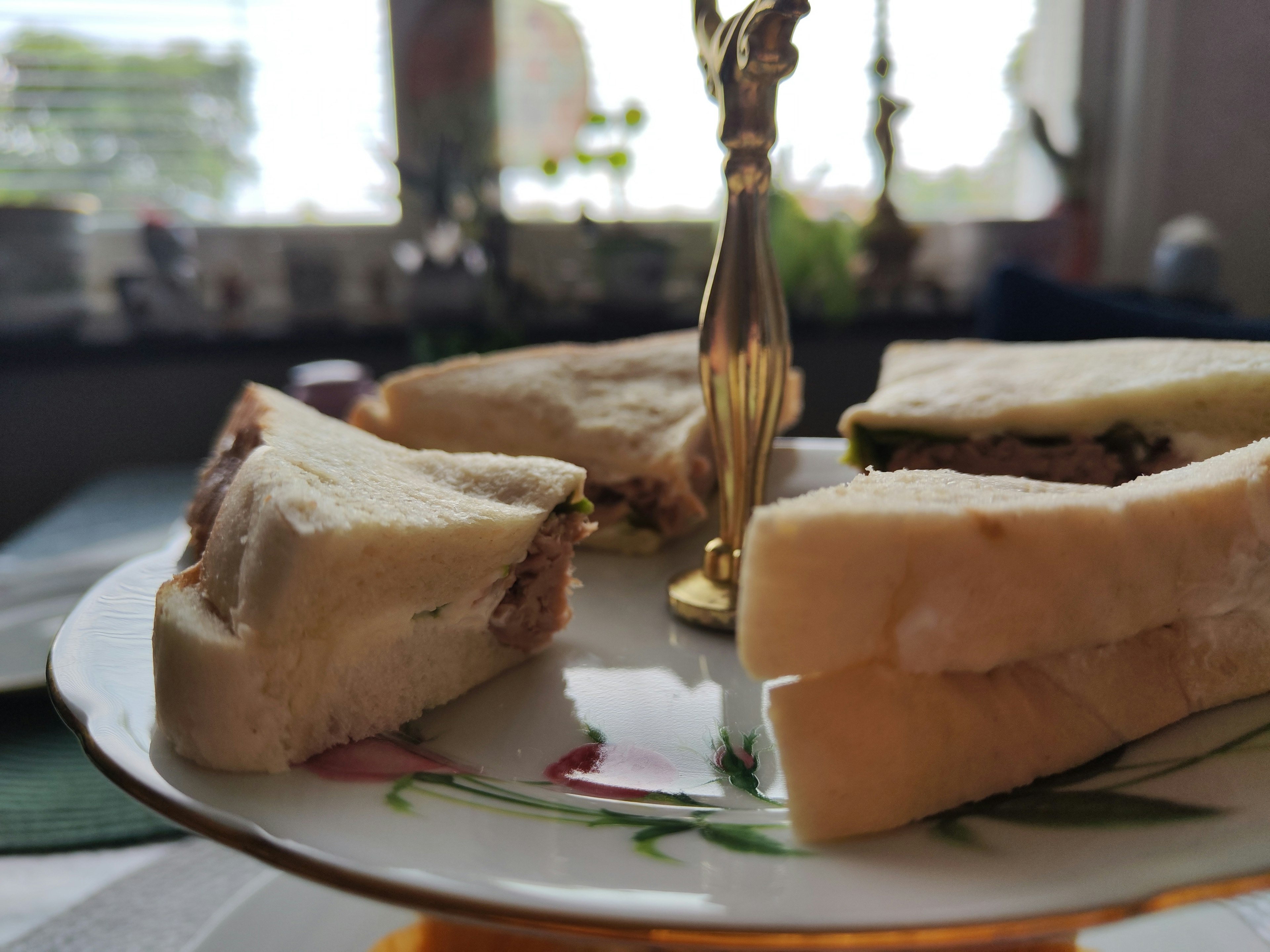 Un plato de sándwiches variados con un soporte dorado