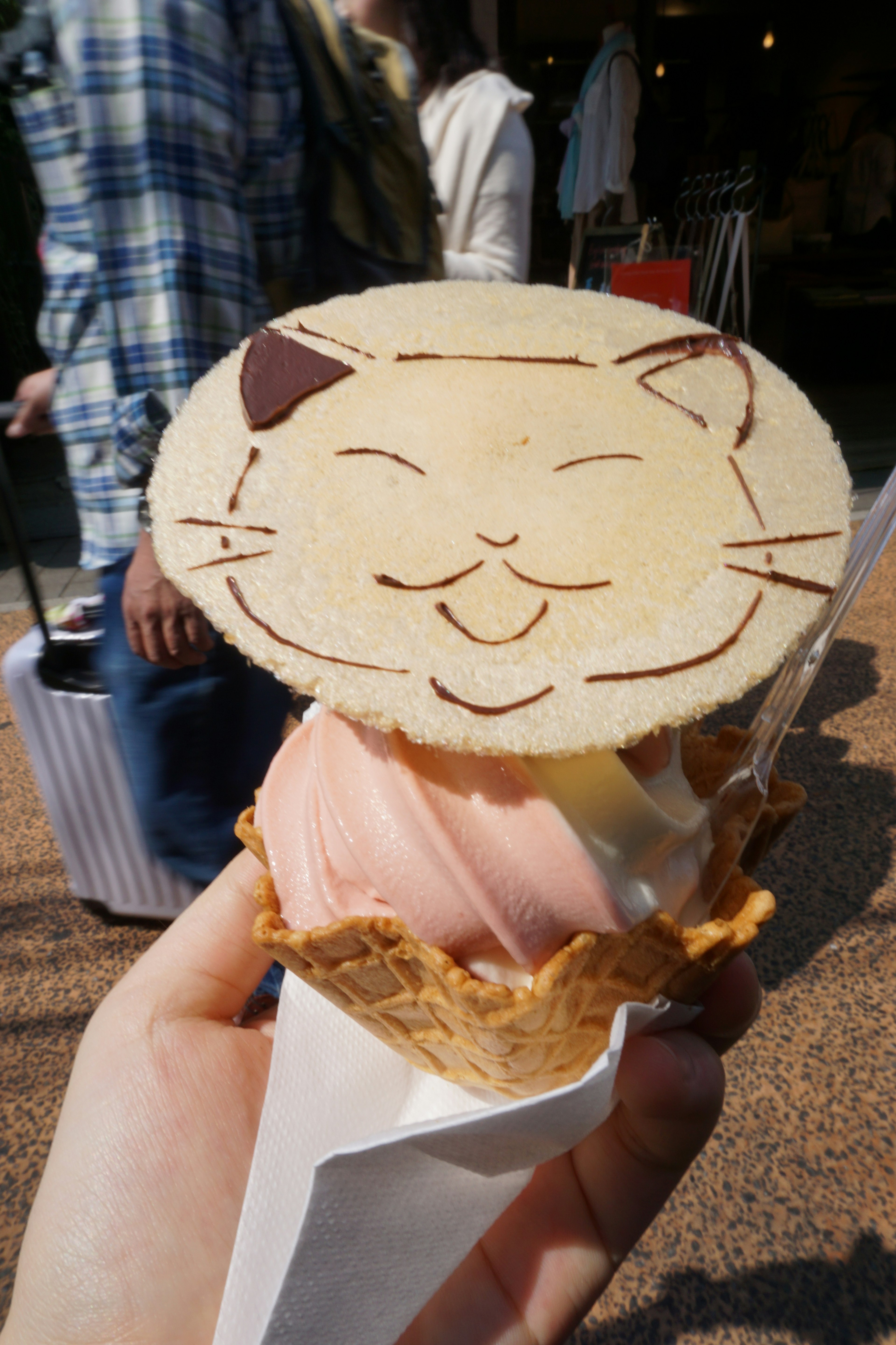 Eine Hand hält ein Eis mit einem Keks in Form eines Katzenkopfes