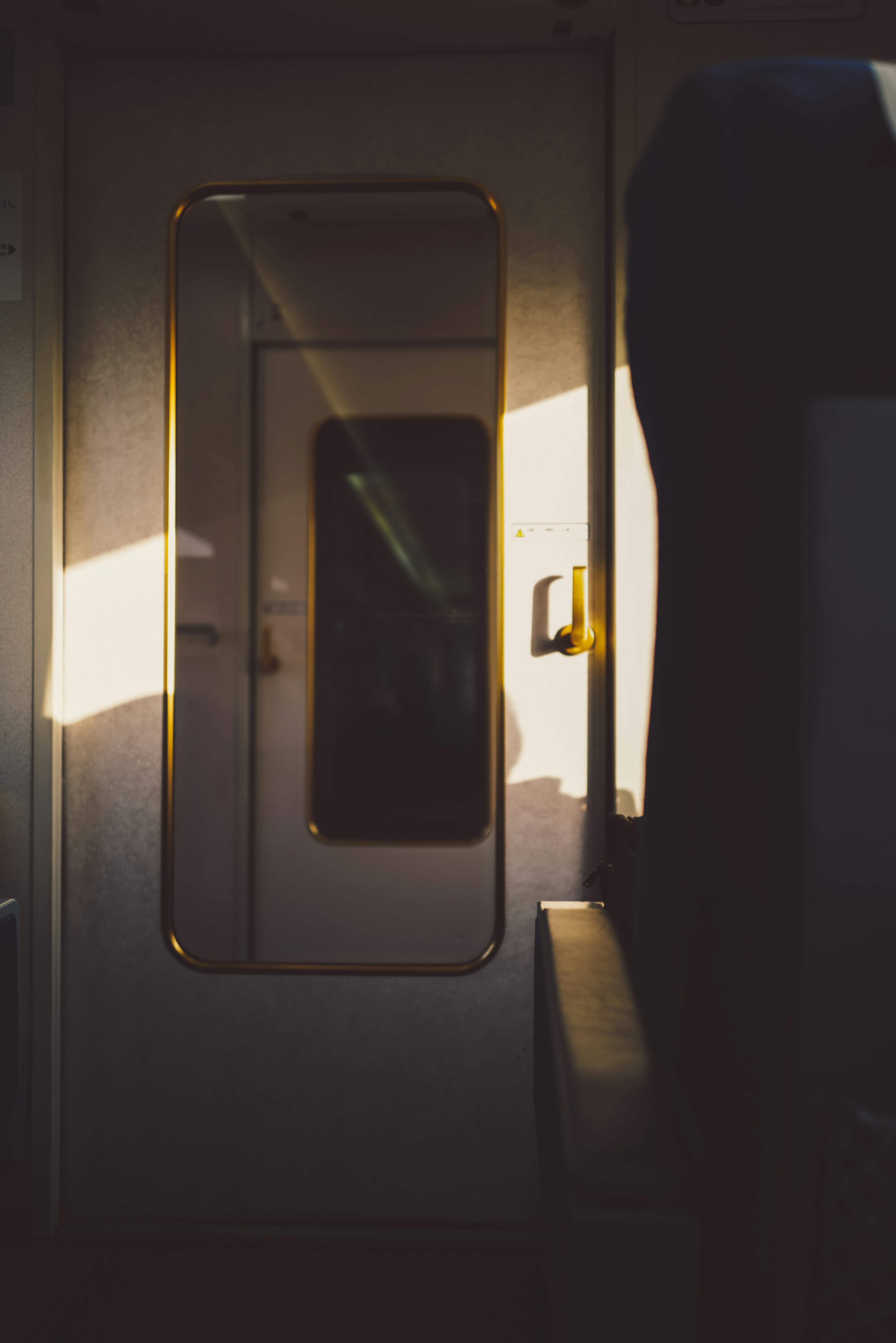 Interior of a train carriage featuring a door and sunlight contrast