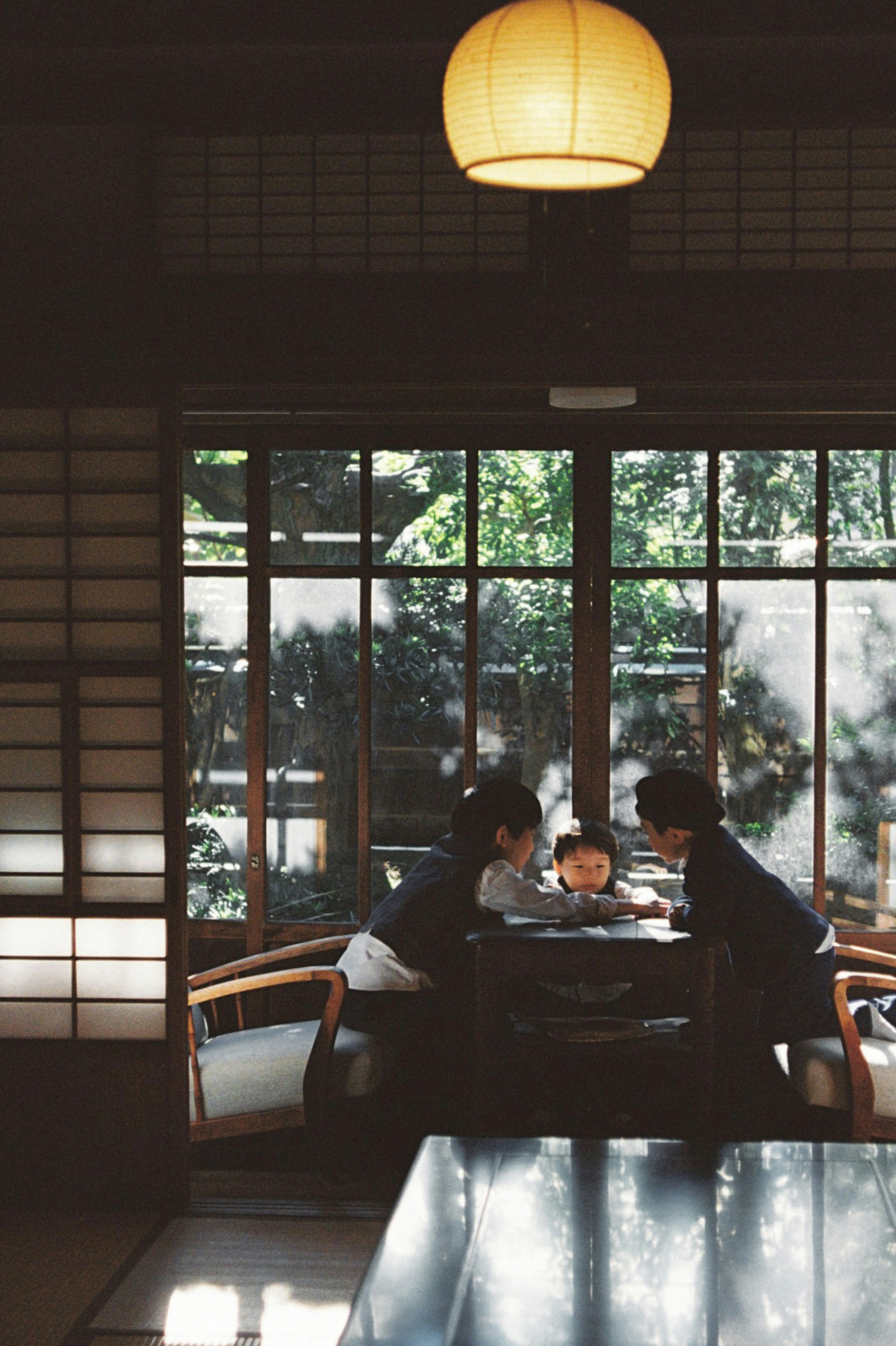 Familie genießt eine Mahlzeit in einem traditionellen japanischen Ambiente mit Sicht auf das Grün durch die Fenster