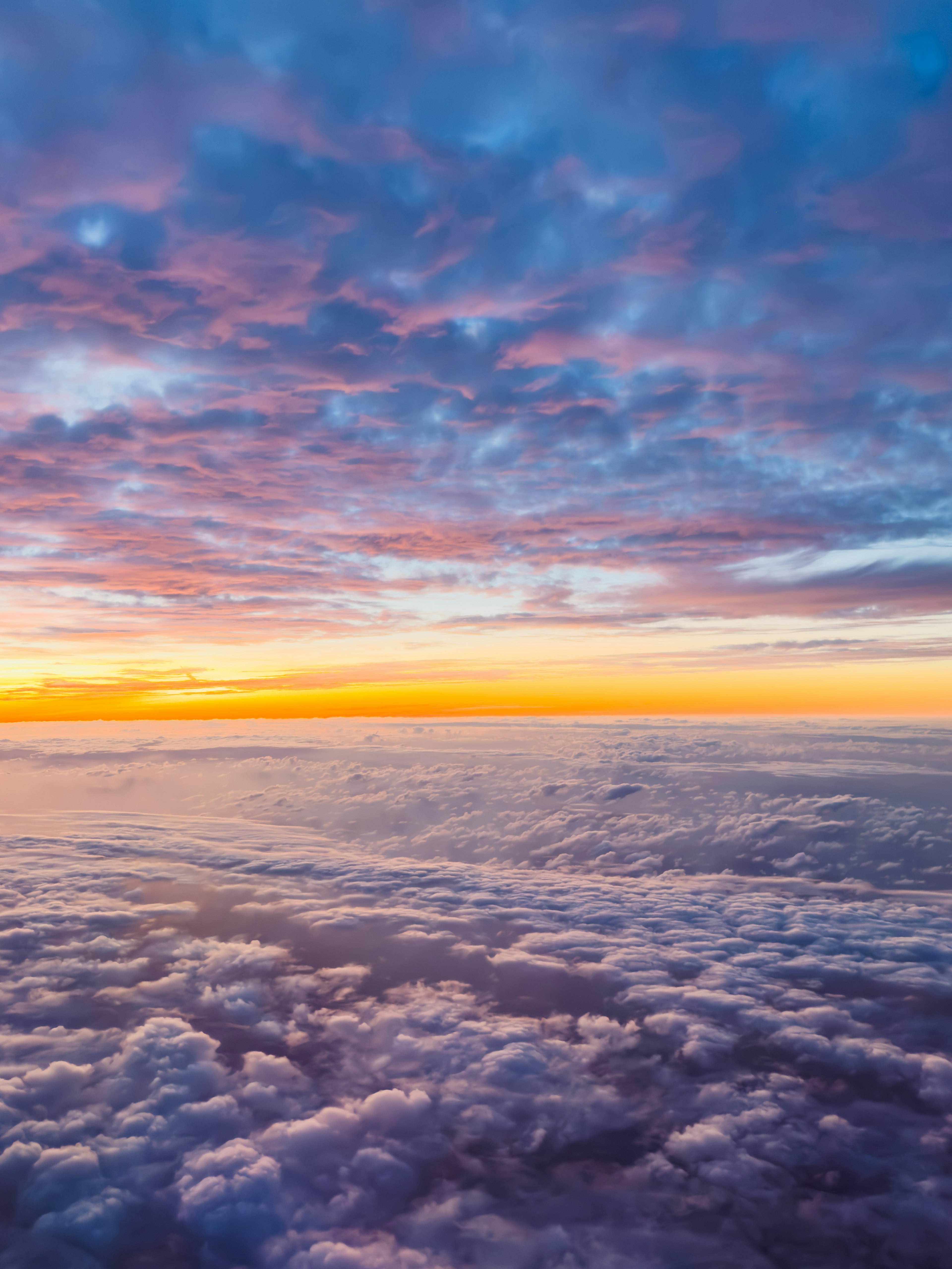 Hermosa vista del cielo con nubes naranjas y moradas al atardecer desde arriba de las nubes