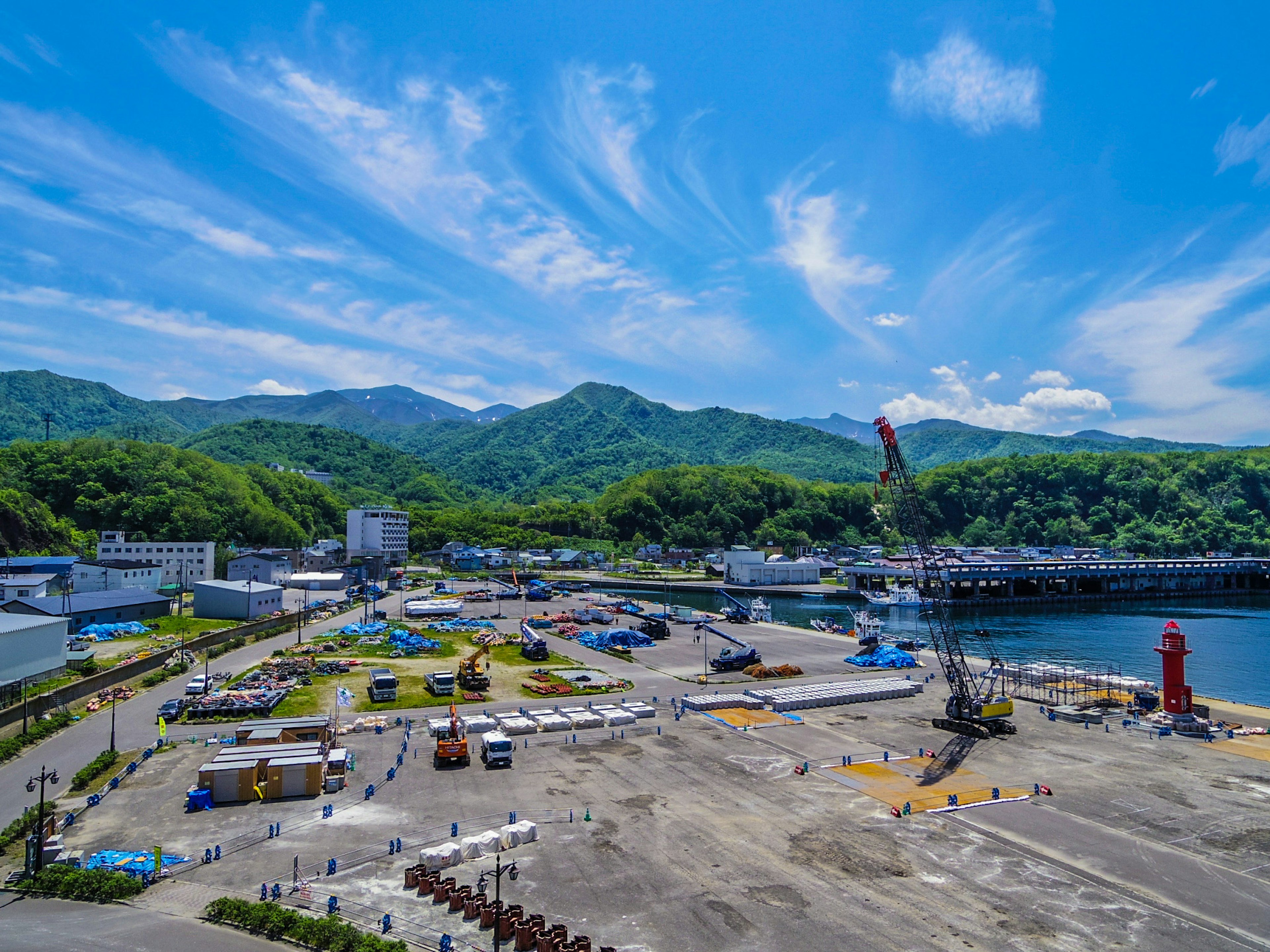 Scenic port view under a beautiful blue sky with green mountains and a crane visible