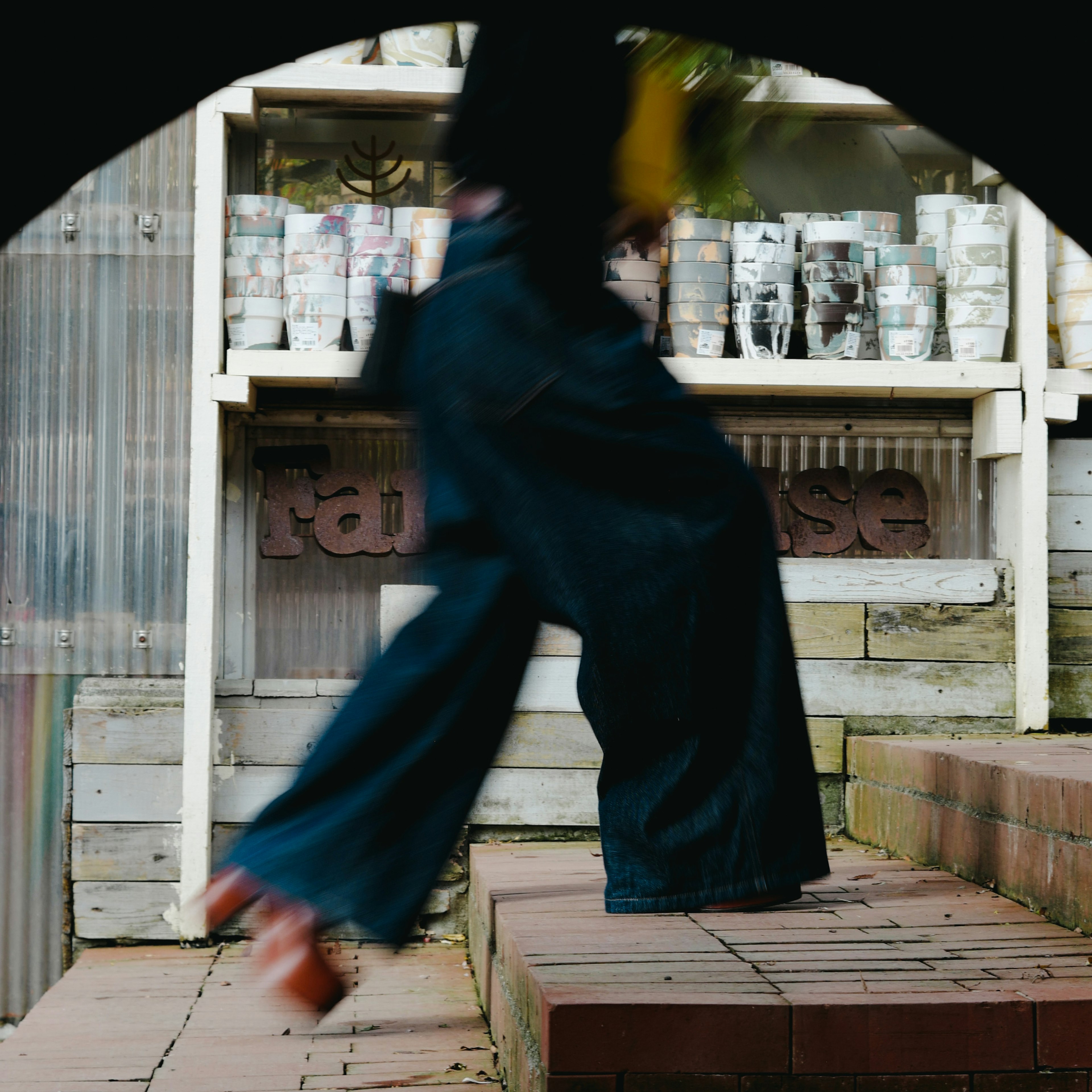 Eine Person in blauen Hosen, die an einer bunten Anzeige von Dosen im Hintergrund vorbeigeht