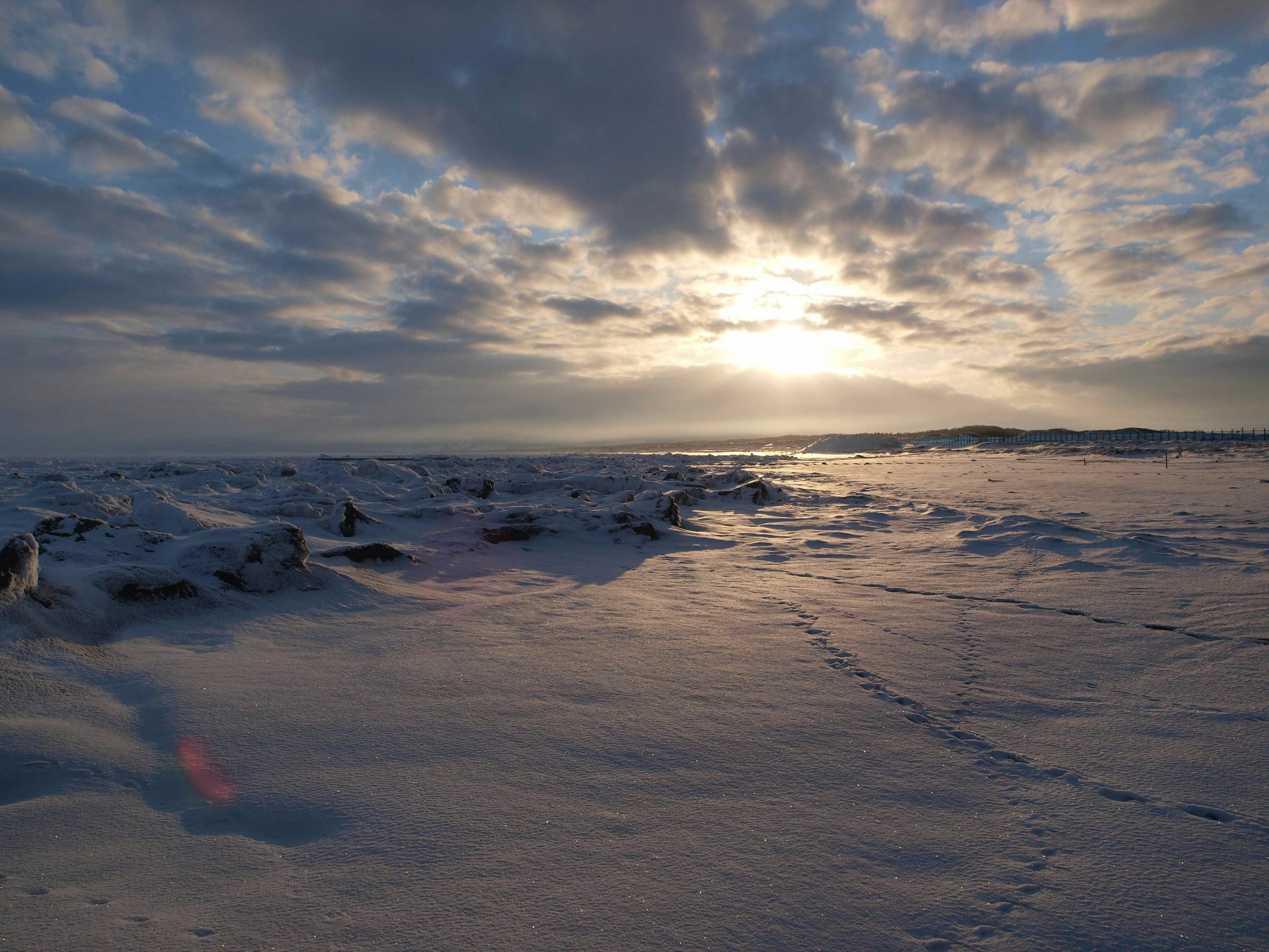 Schöner Sonnenuntergang über einer schneebedeckten Küste mit dramatischen Wolken