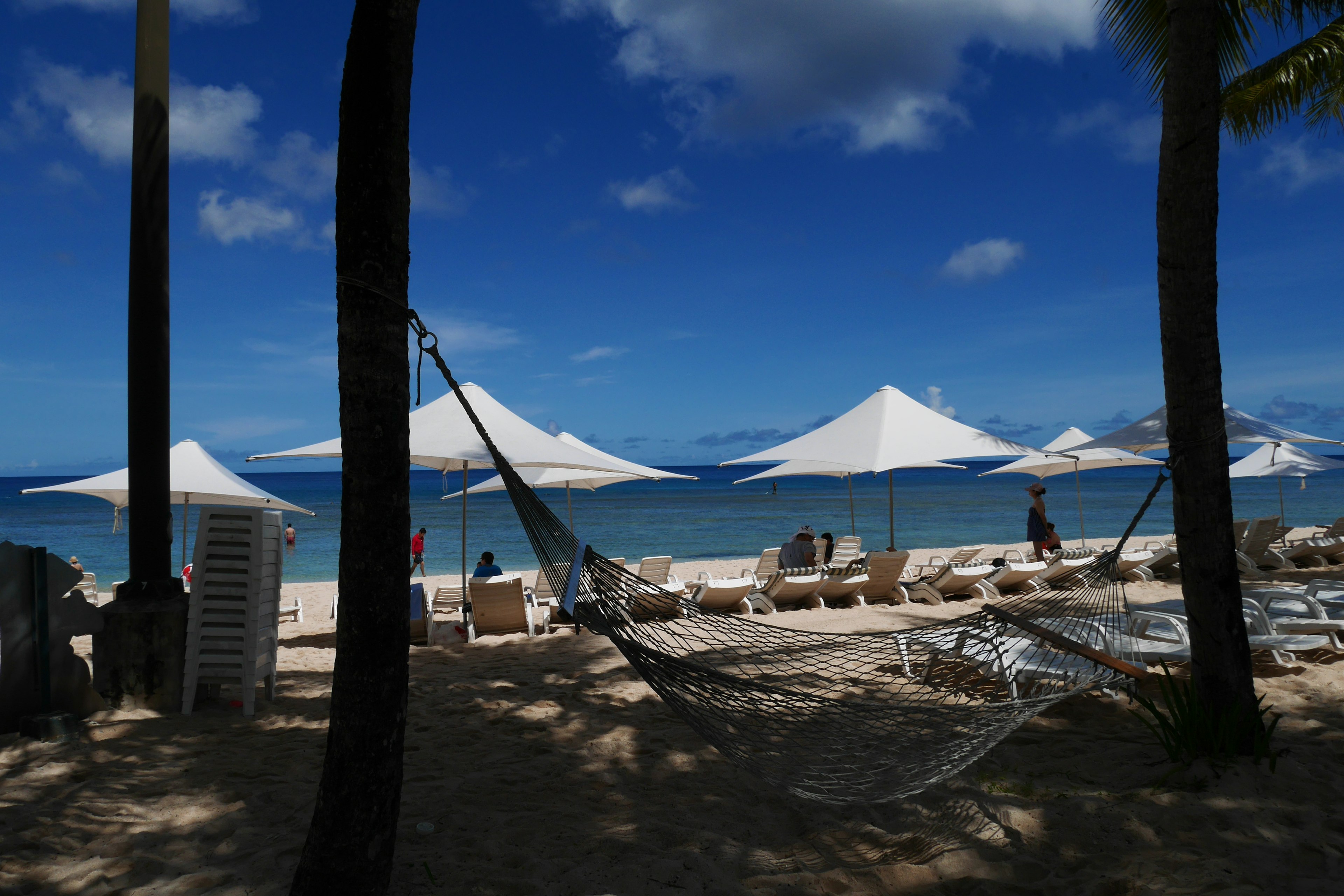 Scène de plage avec des hamacs et des parasols blancs créant une atmosphère relaxante