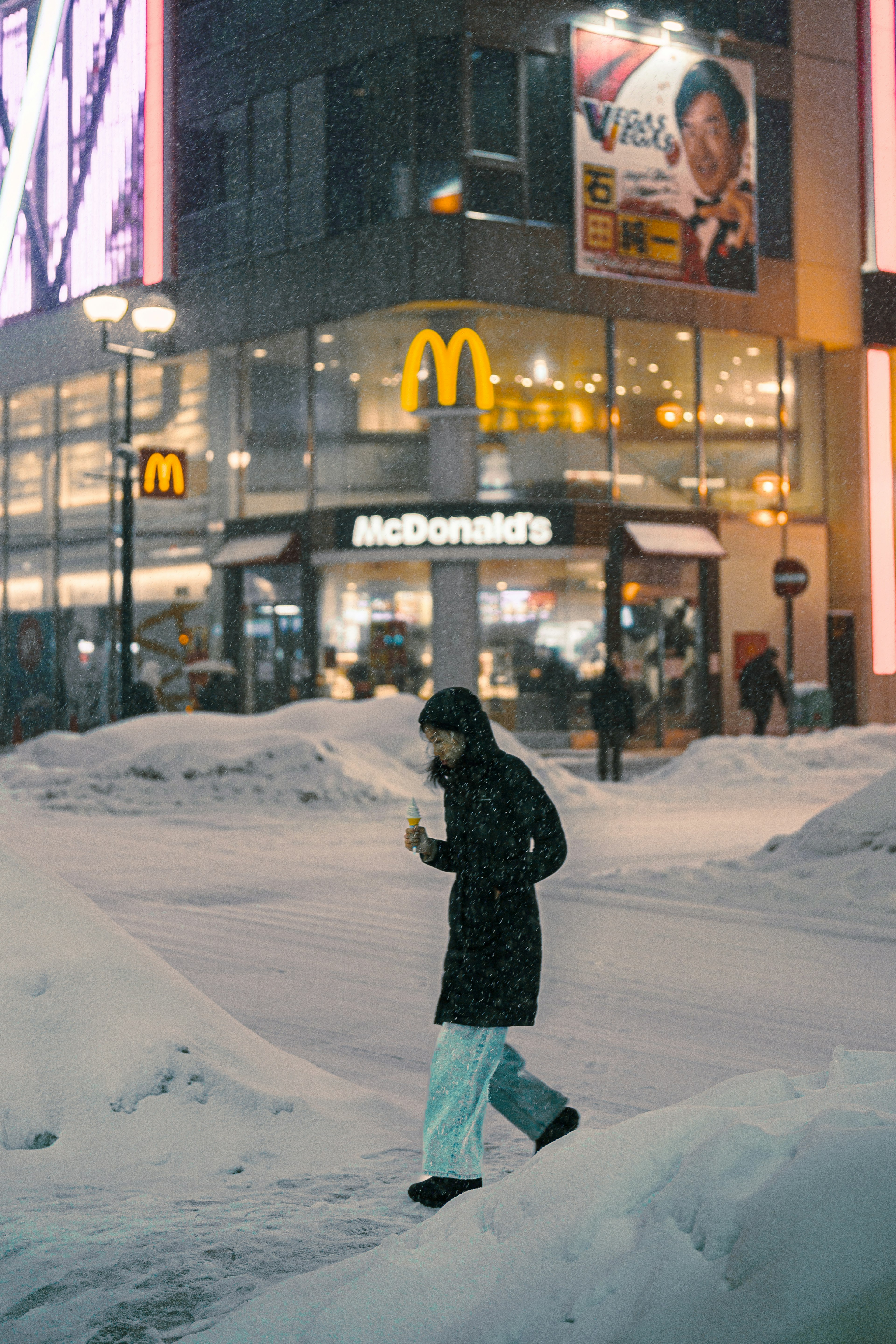 Una persona che cammina nella neve con un'insegna McDonald's sullo sfondo