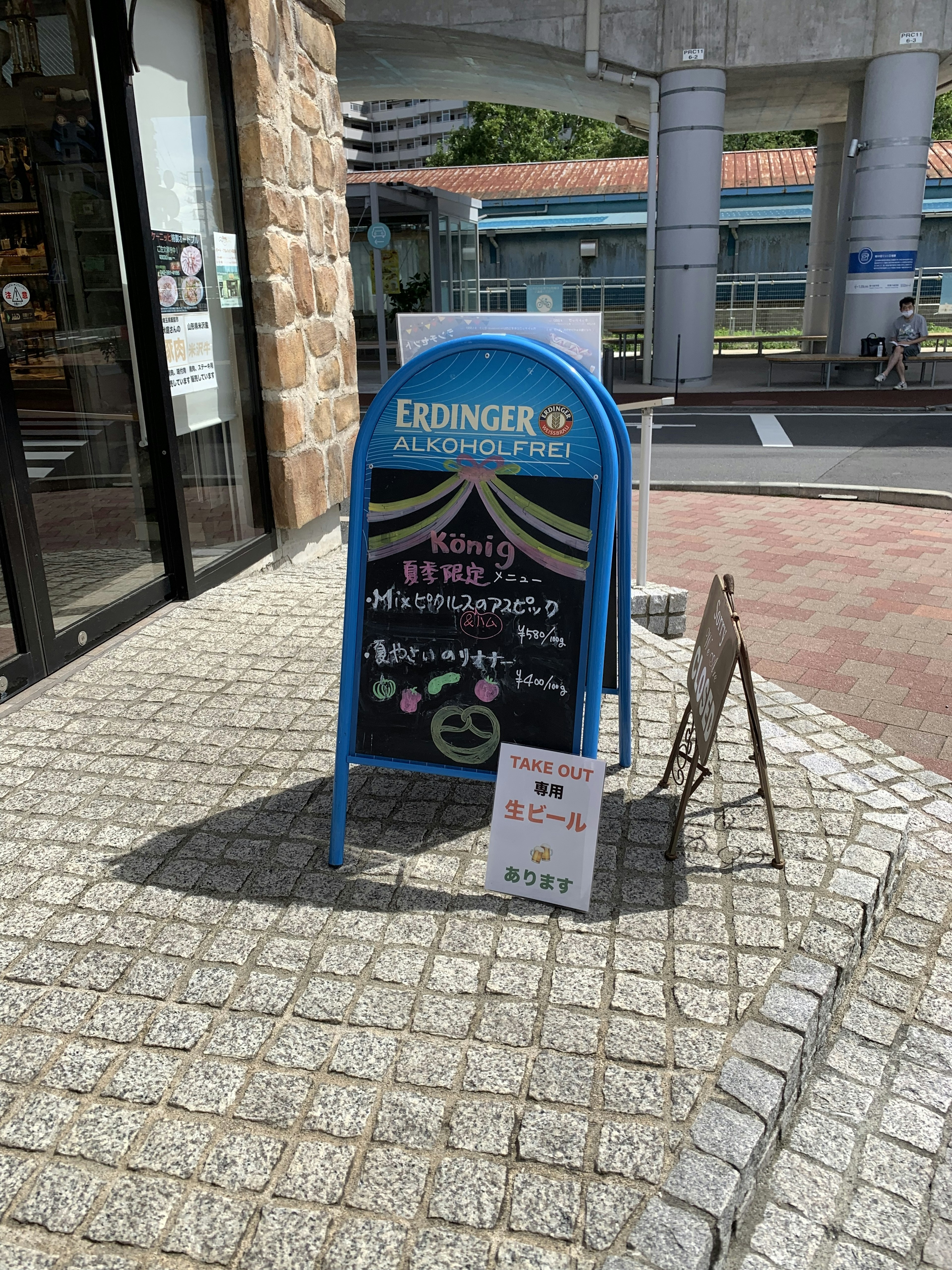 A blue signboard stands in front of a store featuring menu and event information