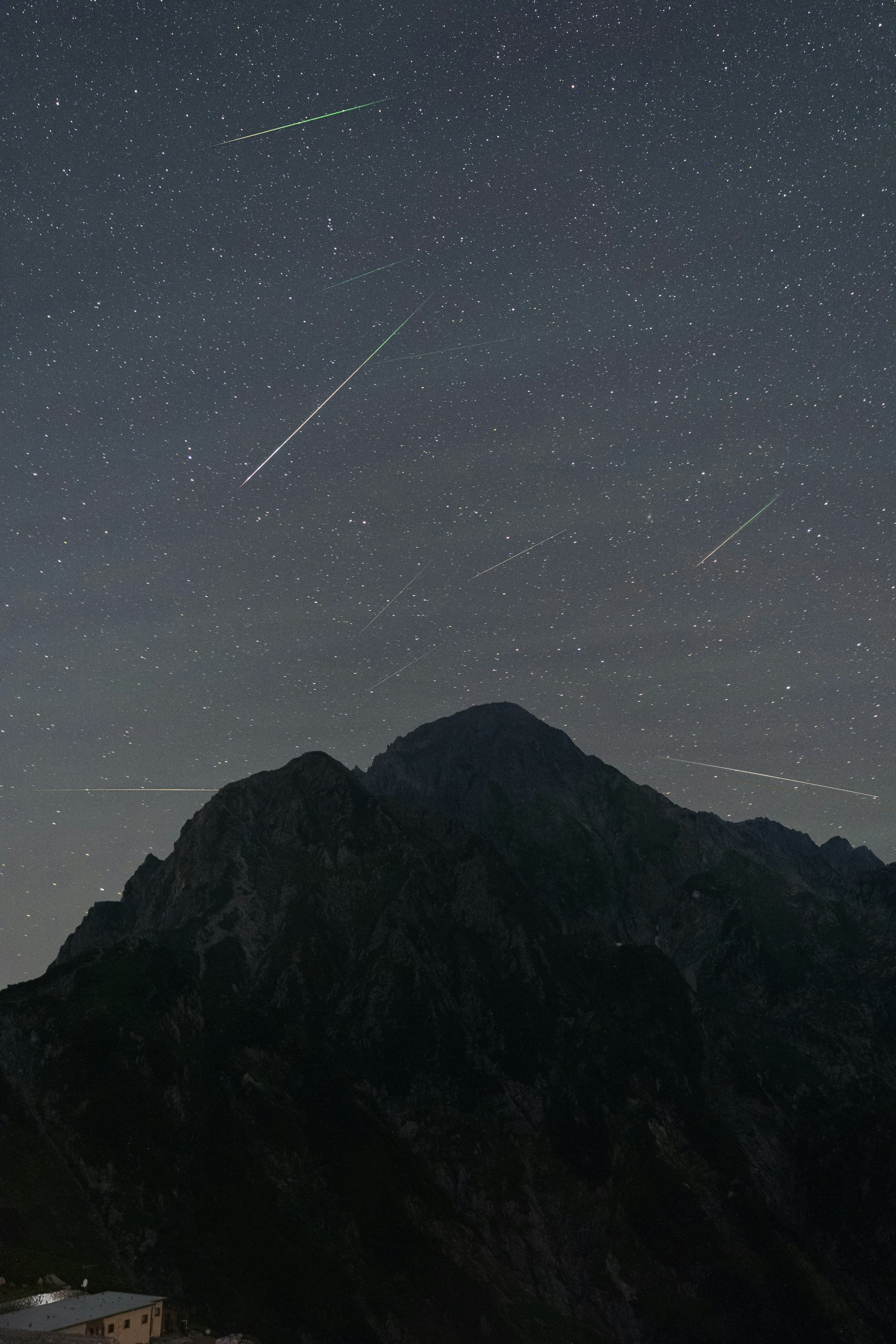 Paisaje montañoso con estrellas fugaces bajo un cielo estrellado