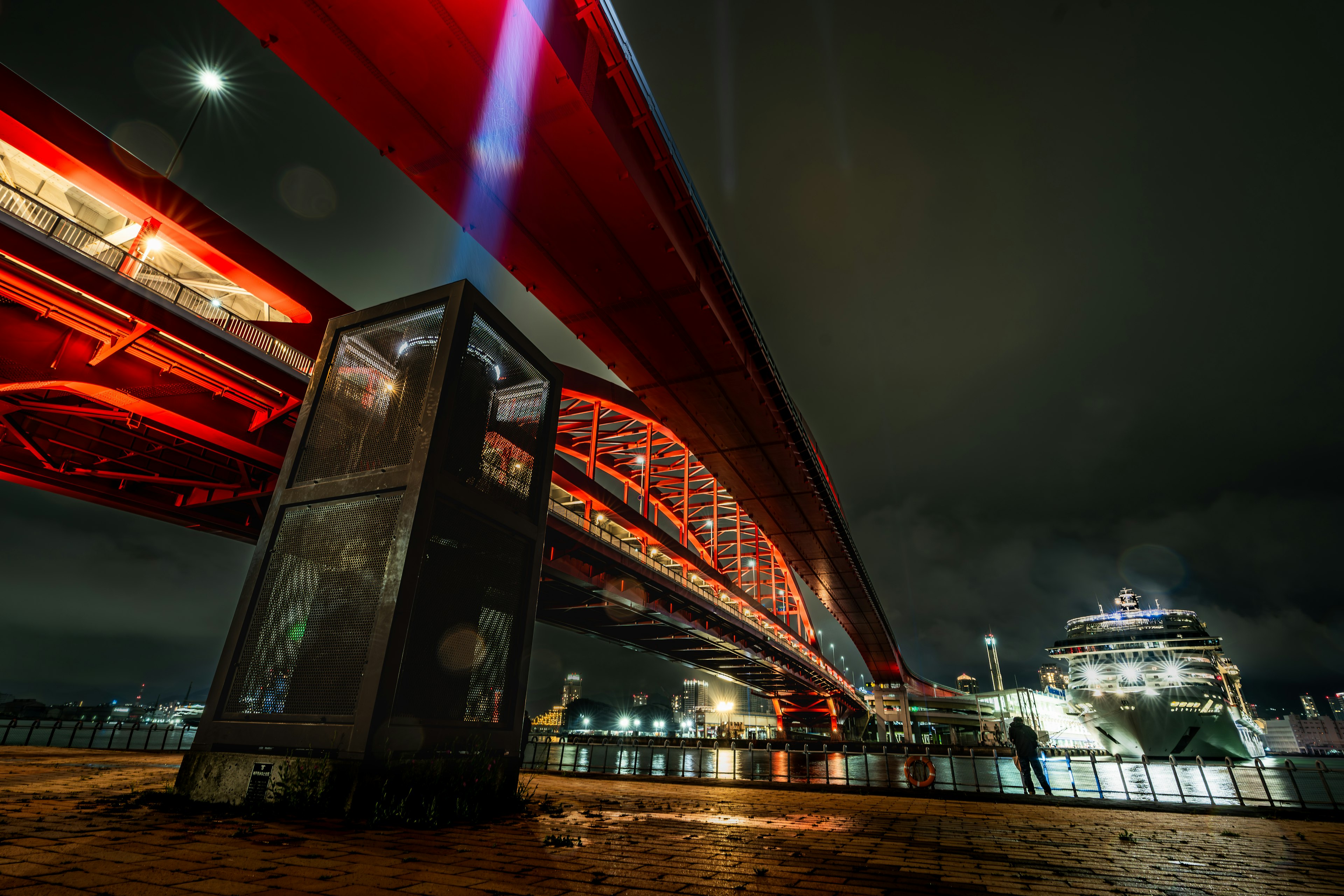 Night scene featuring a striking red bridge and reflections on the water