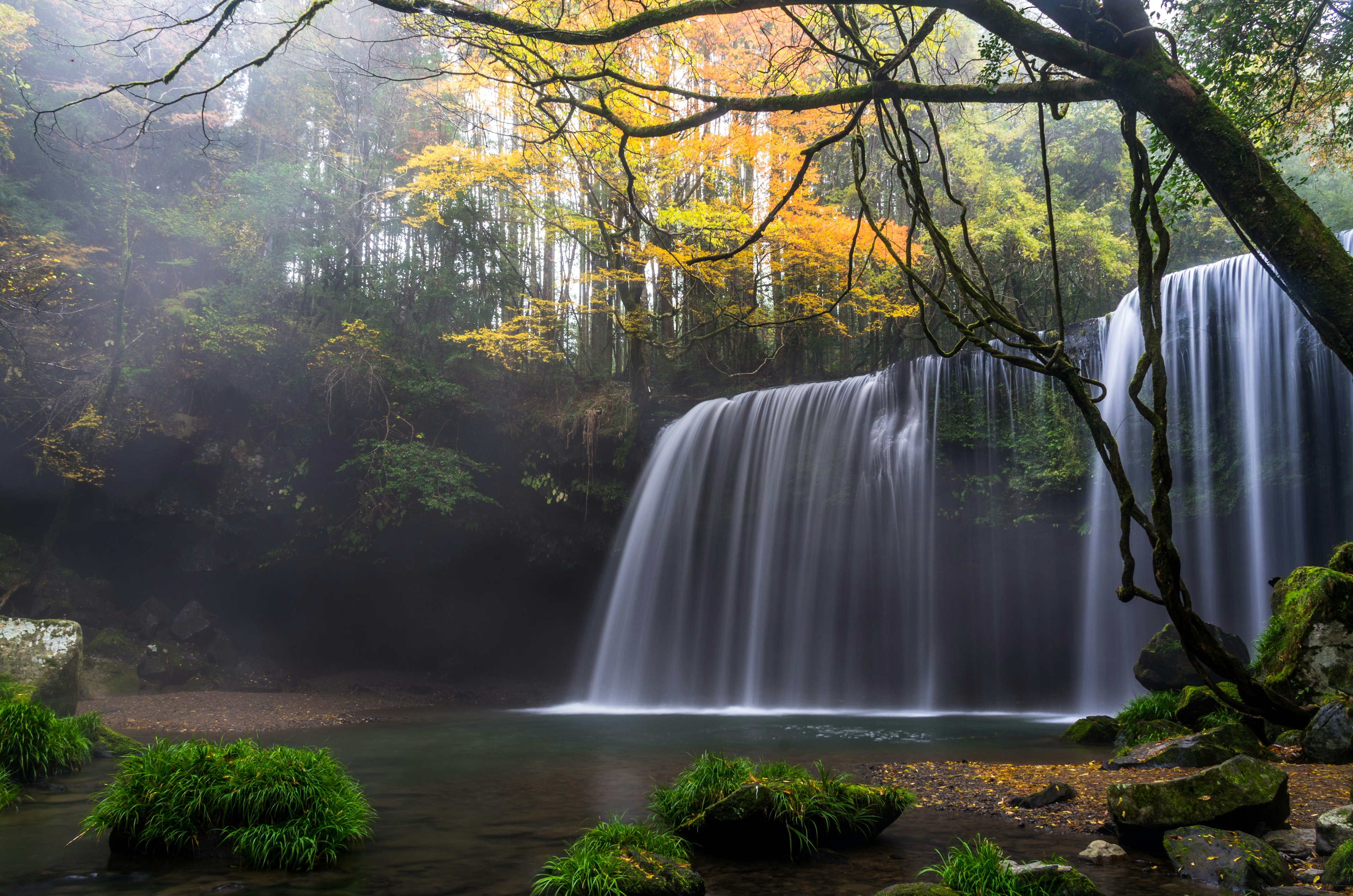 Ein ruhiger Wasserfall umgeben von Herbstbäumen