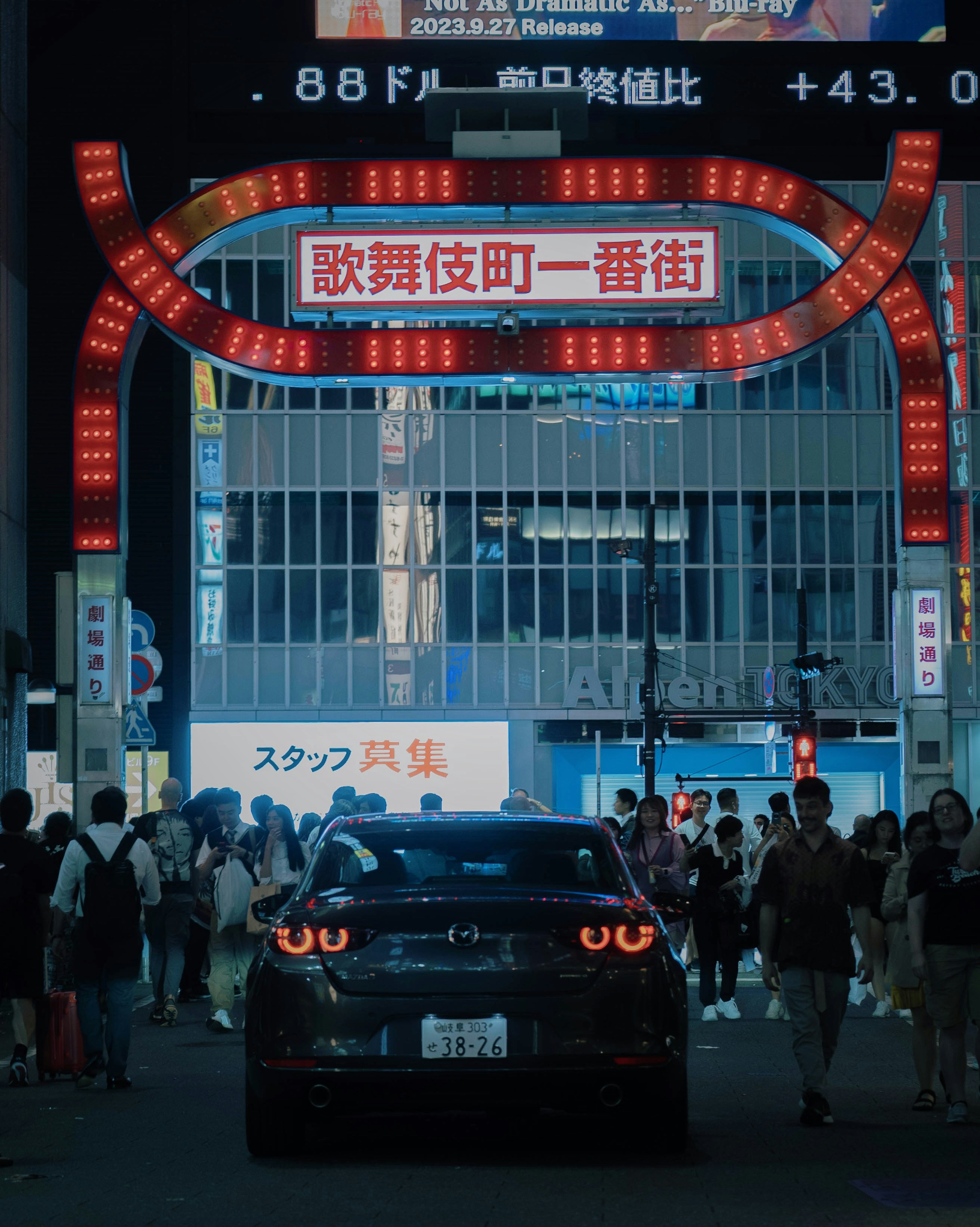 暗い街の中にある赤いネオンのアーチと車の後ろ姿