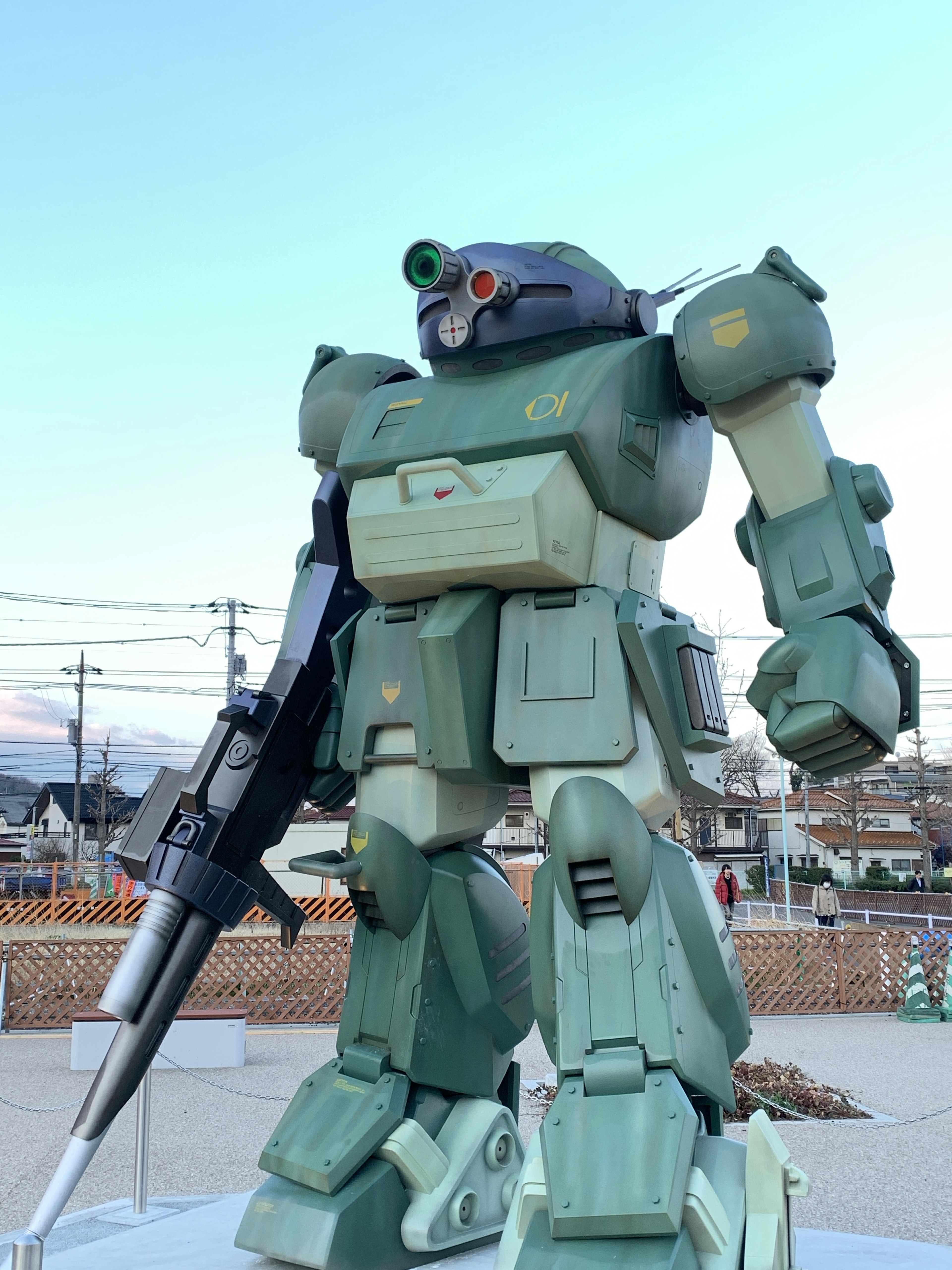 Une statue de robot vert se tient en avant-plan contre un ciel bleu