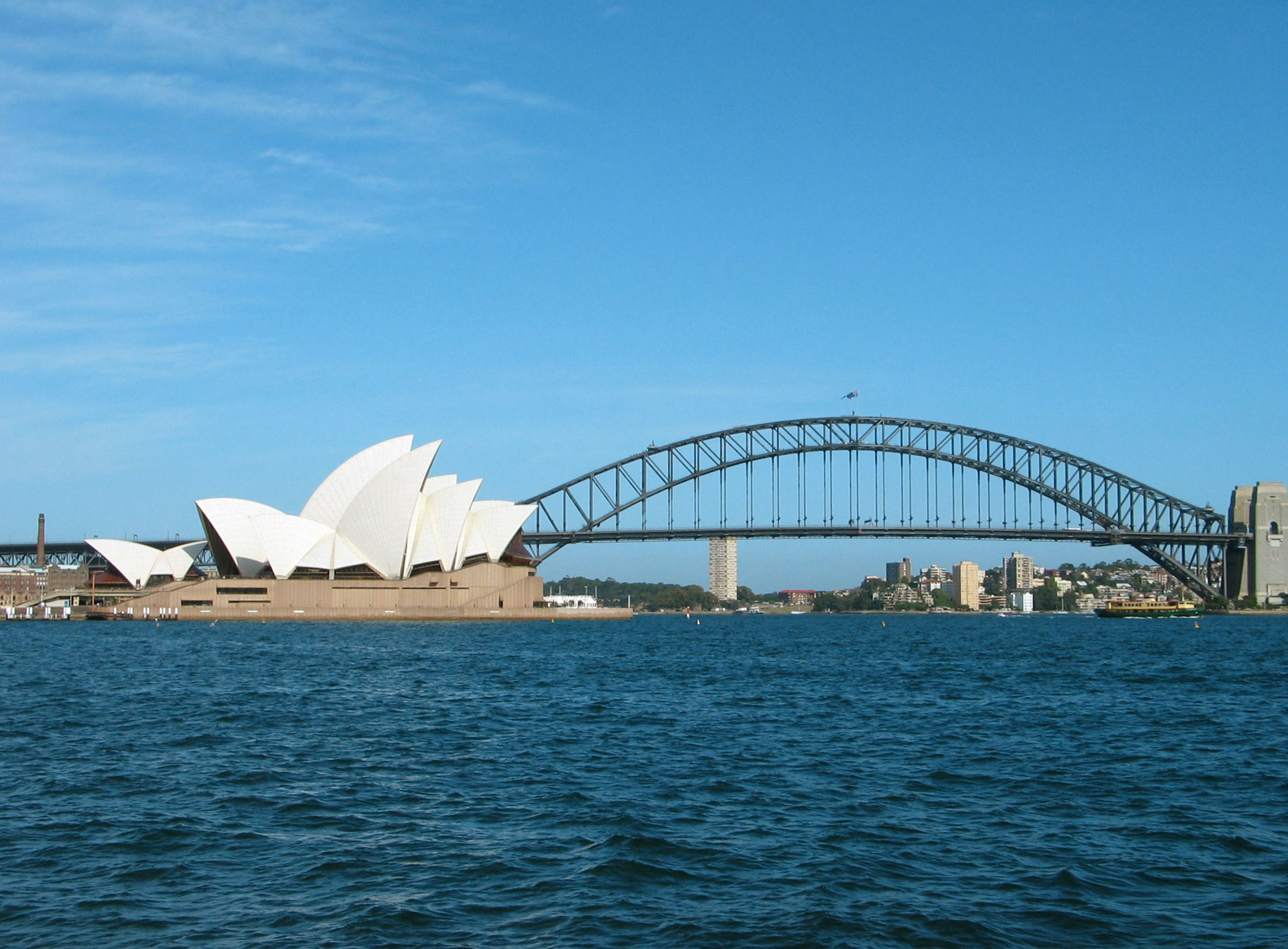 View of Sydney Opera House and Harbour Bridge with blue water and clear sky