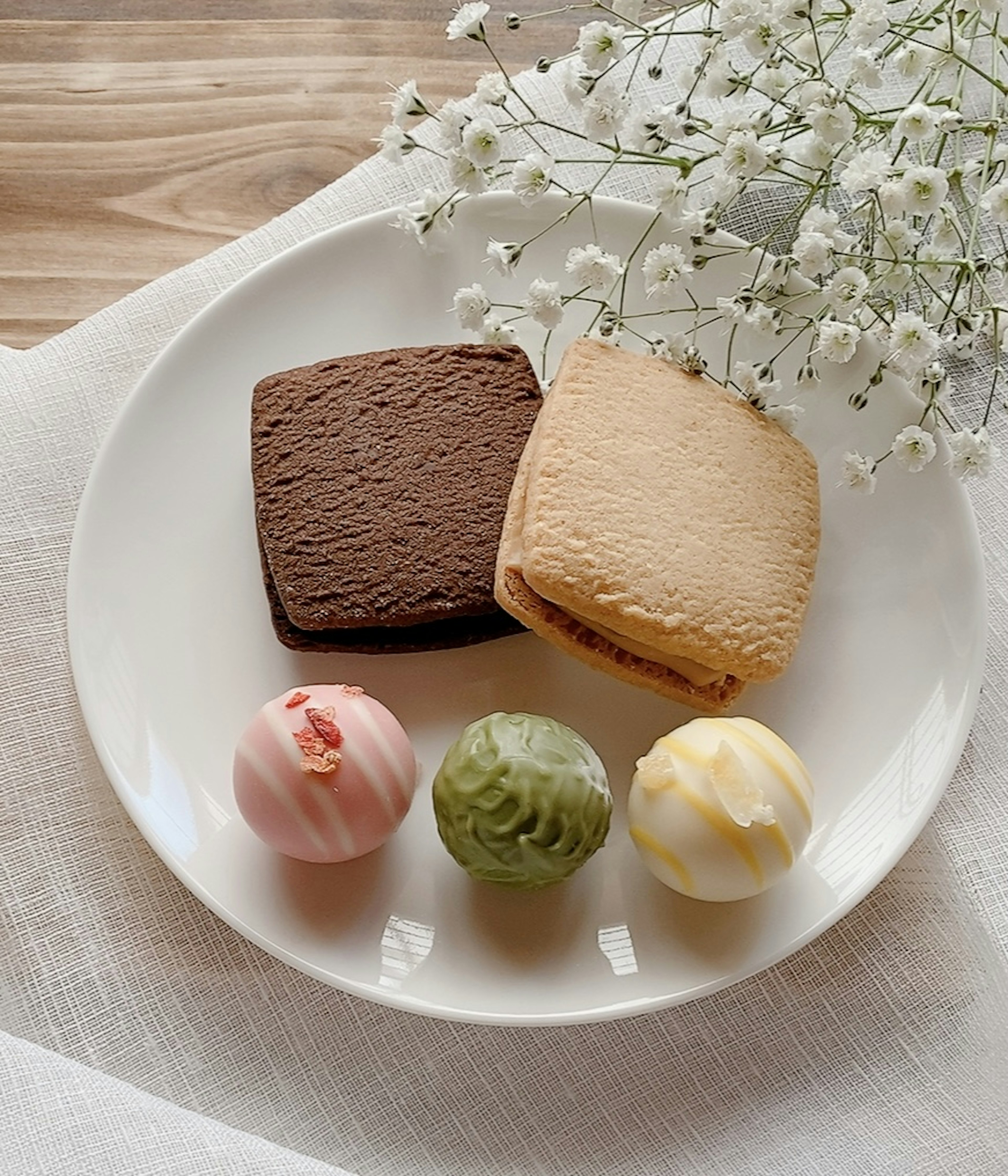 A plate with assorted sweets and a small flower arrangement