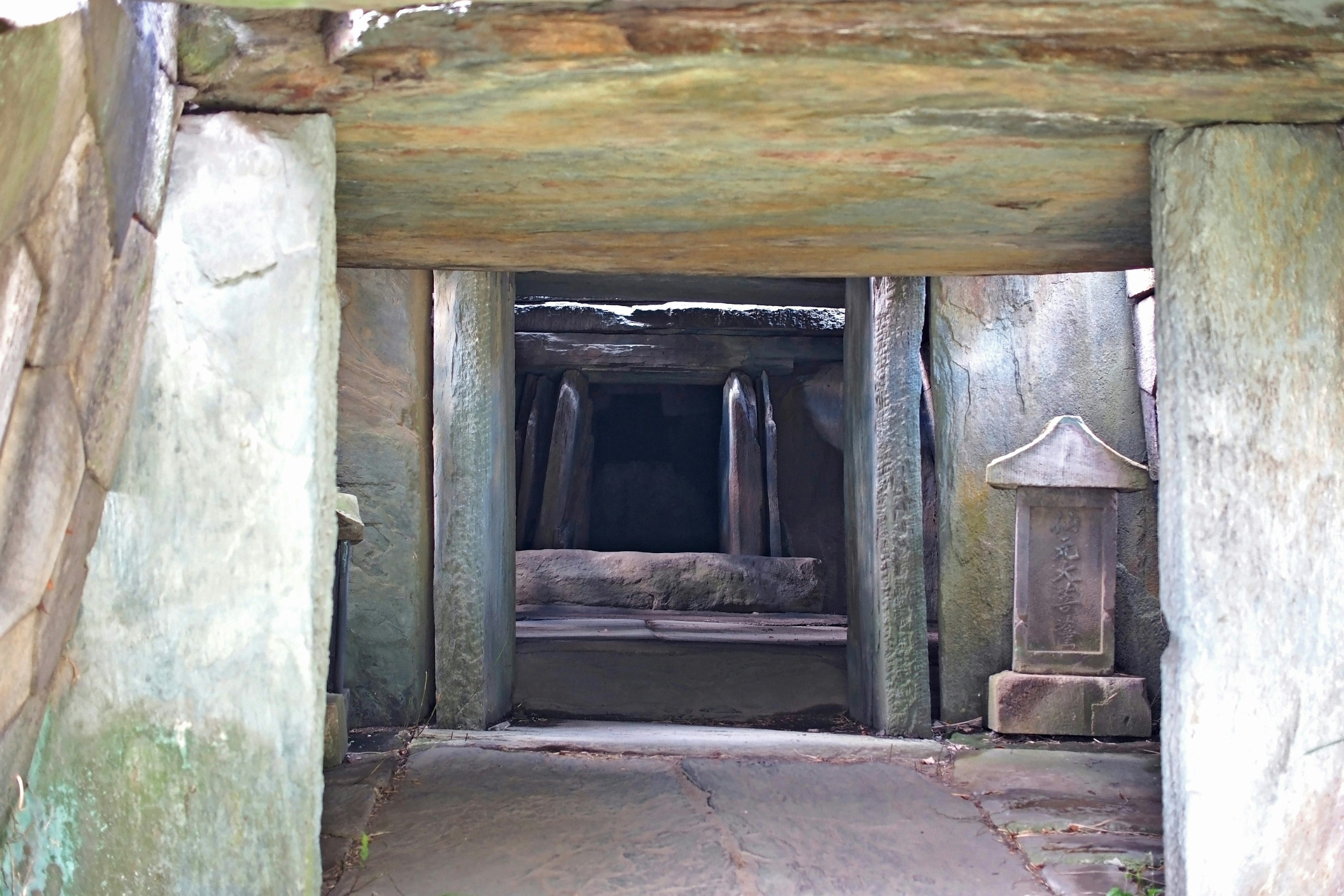 Entrada de una antigua cueva funeraria con pilares de piedra y un interior oscuro