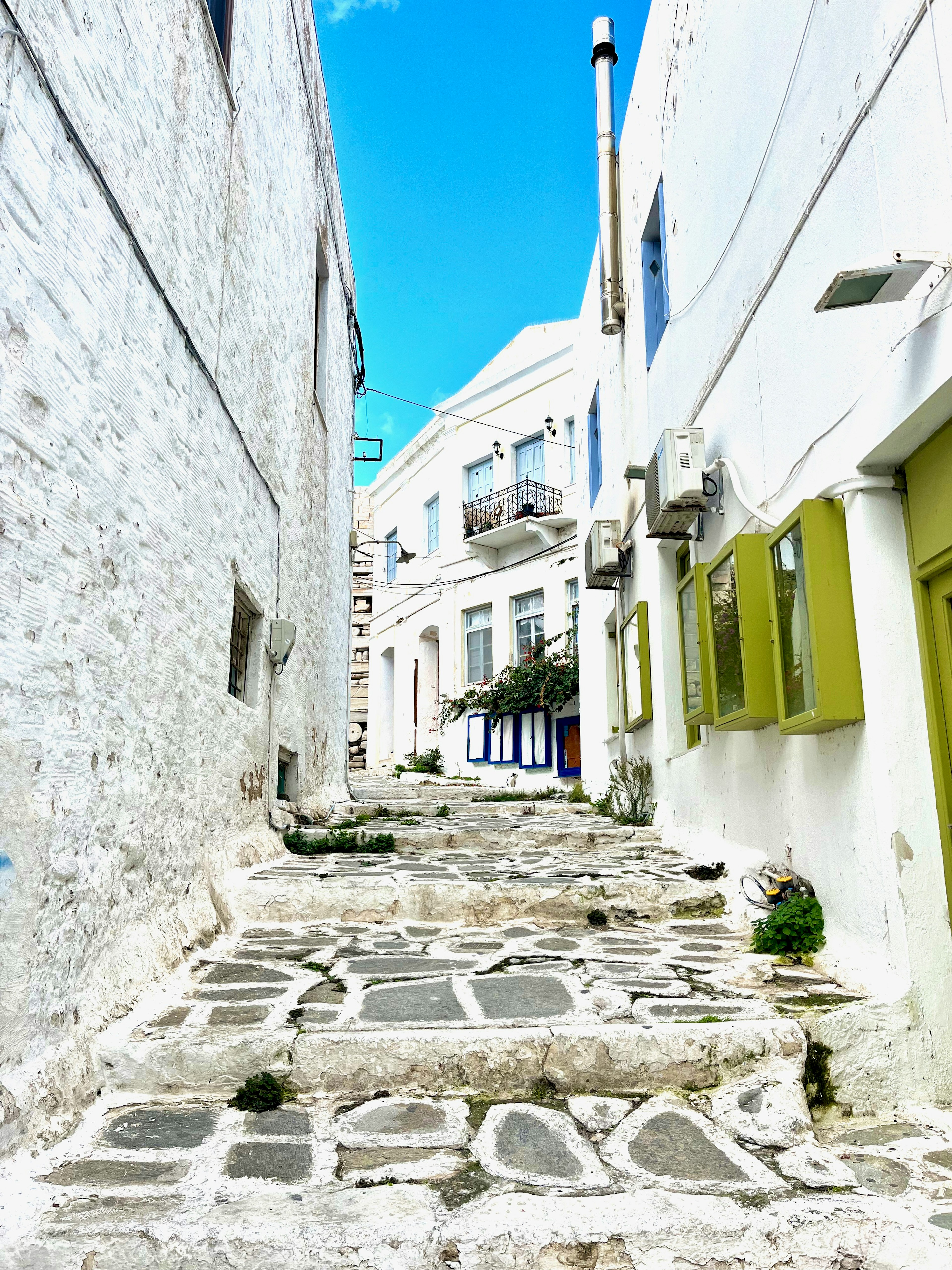 Narrow alleyway with white buildings and stone pathway