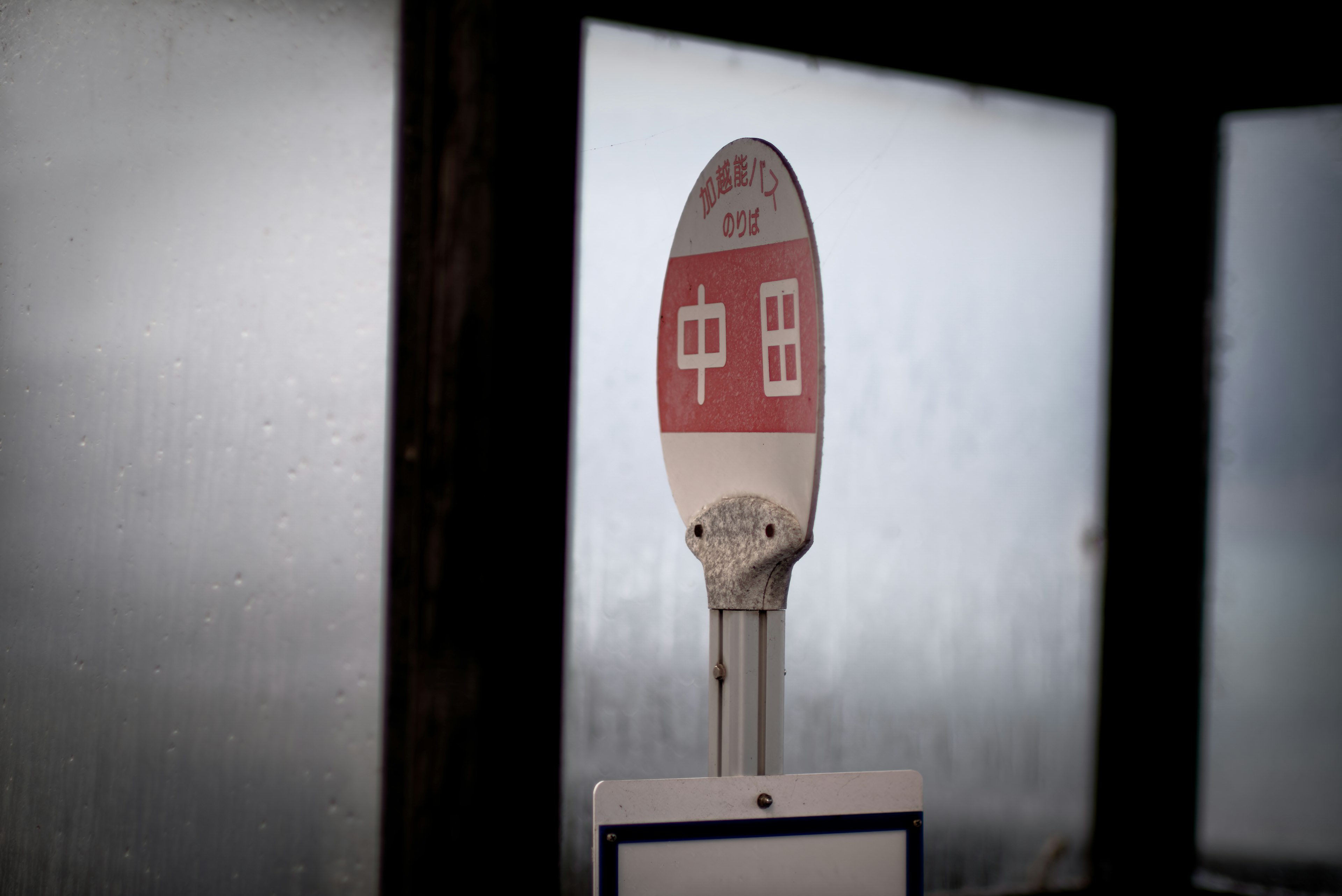 Bus stop sign behind fogged glass