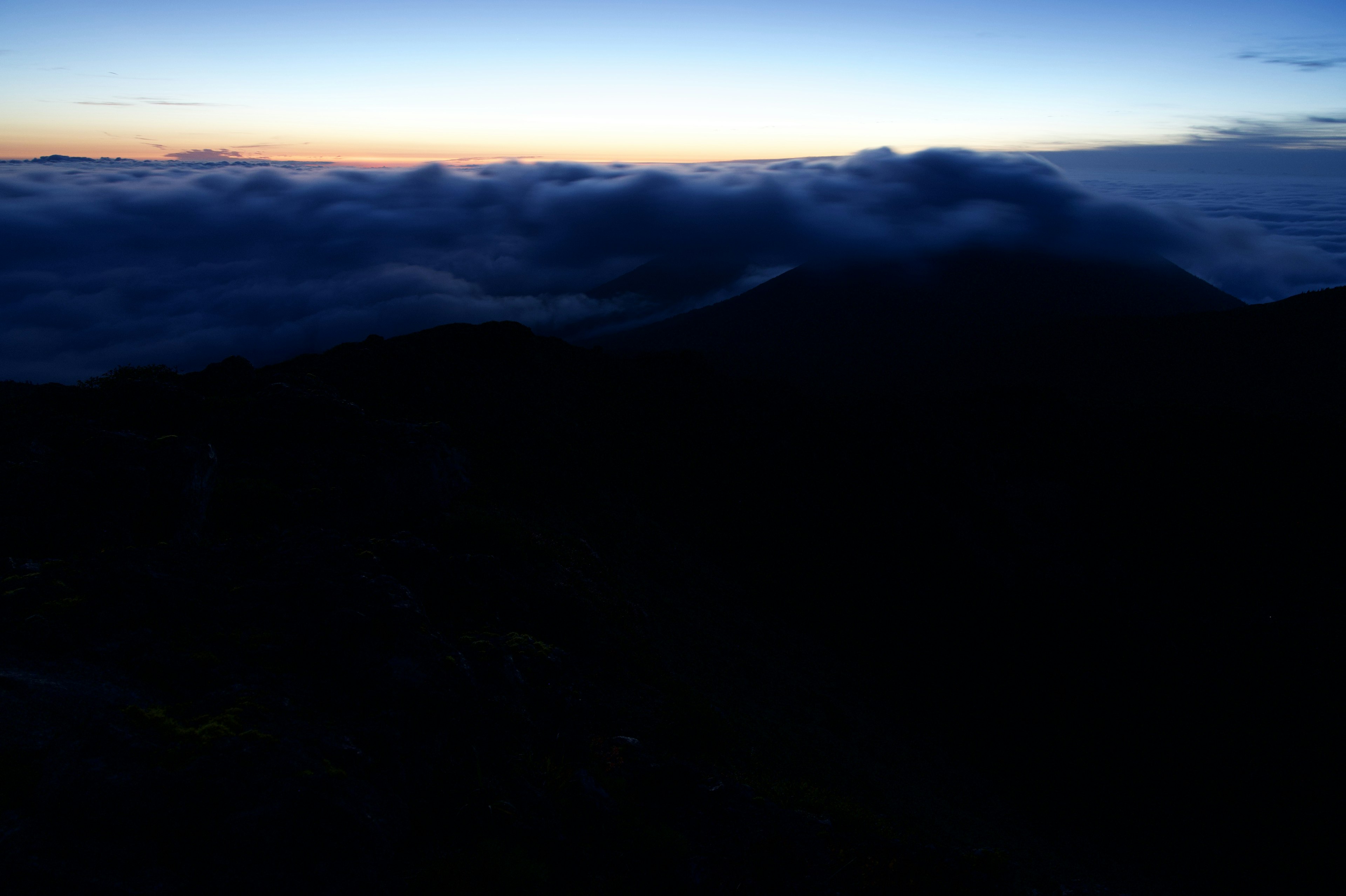 Silhouette di montagne sopra un mare di nuvole con luce dell'alba