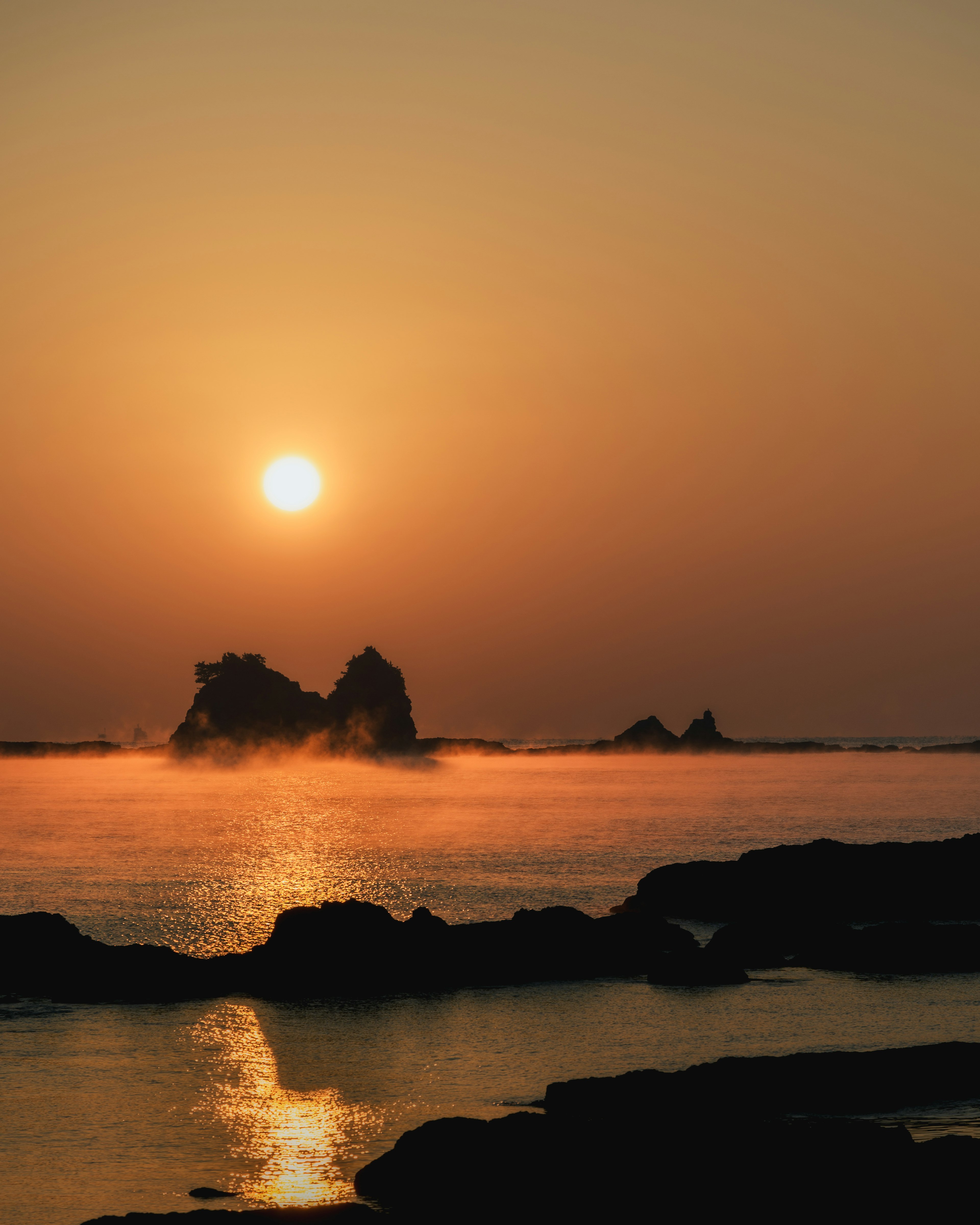 夕日が海に映る美しい風景 岩と霧が印象的