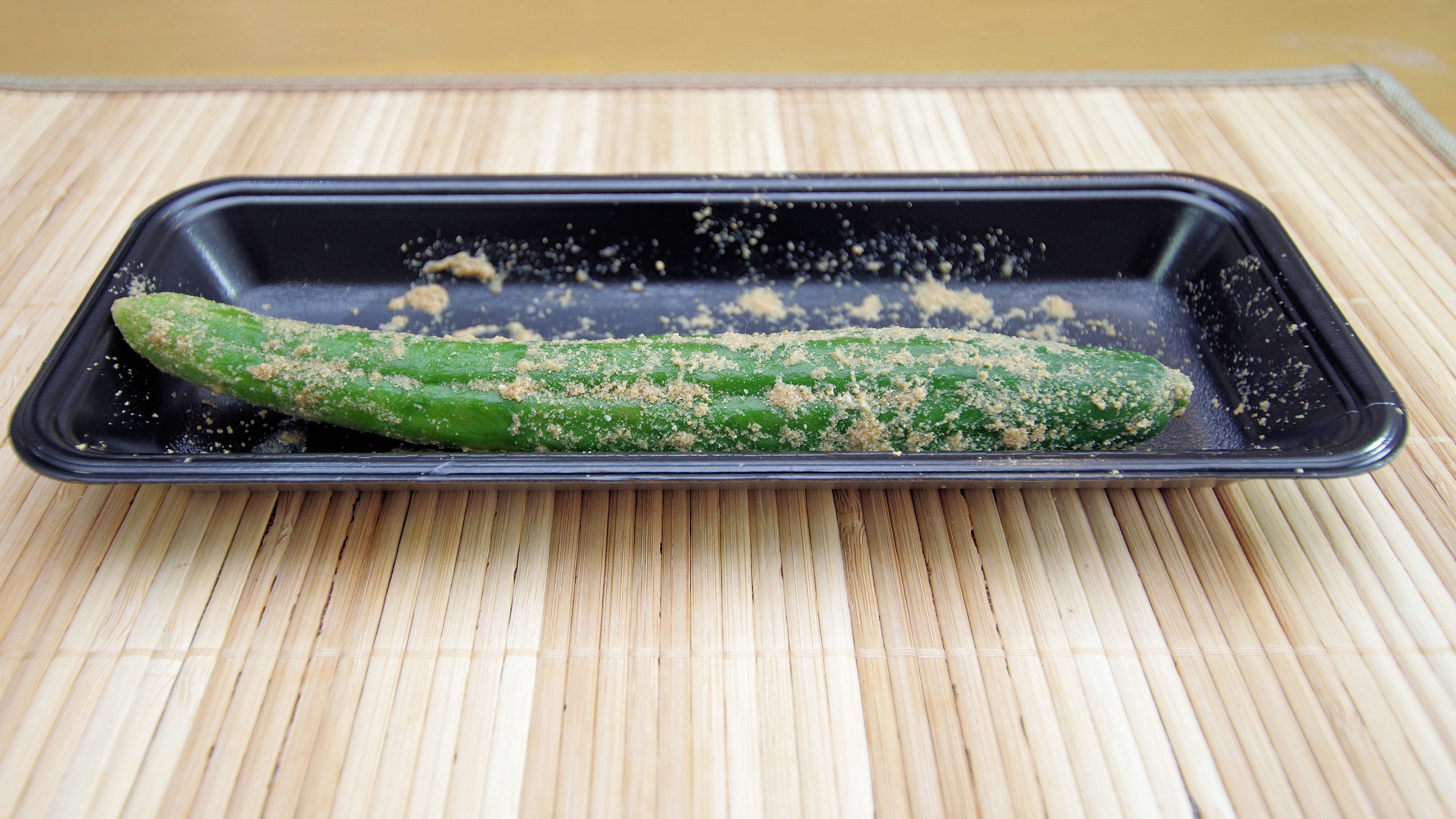 Cucumber on a black tray sprinkled with seasoning