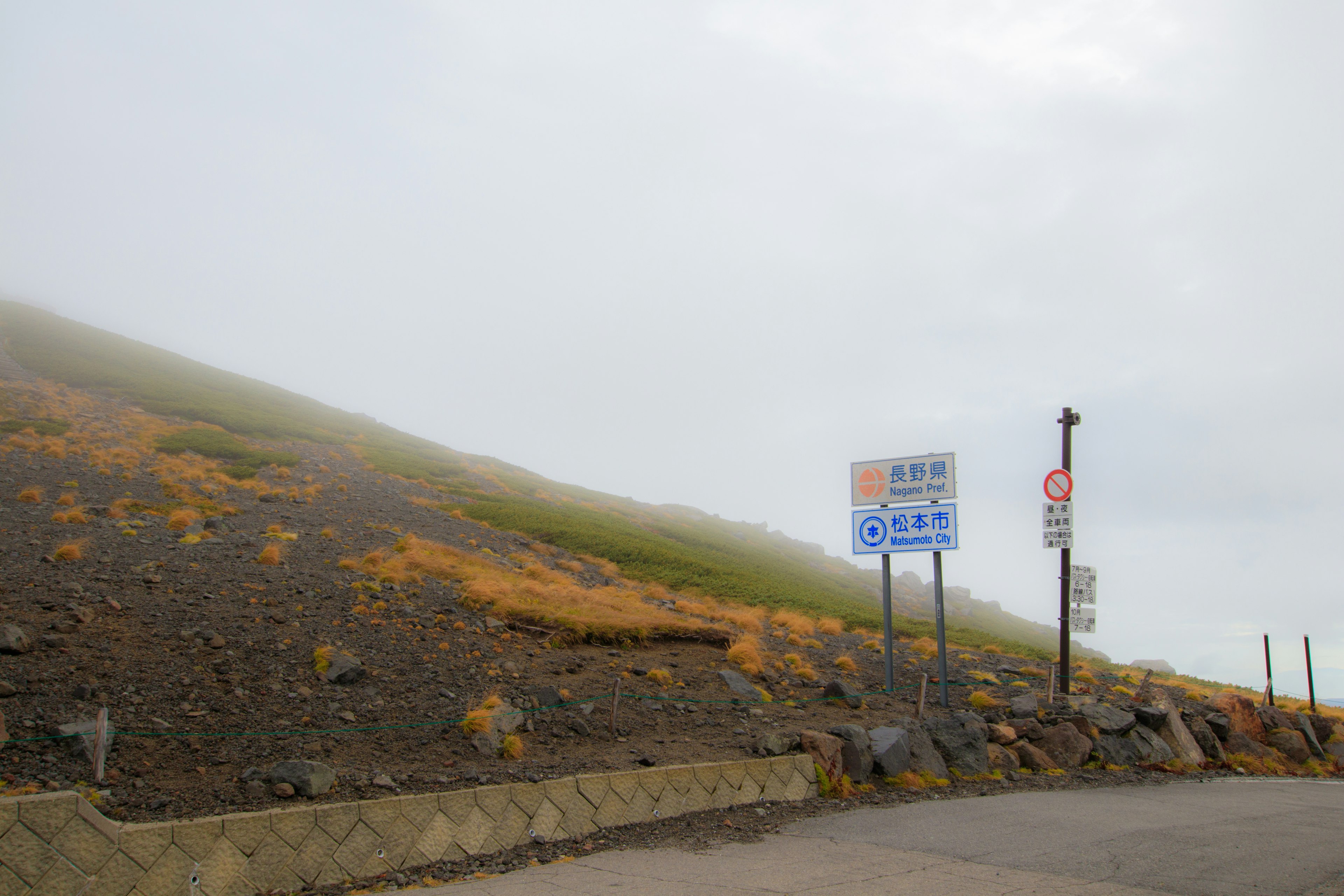 霧に包まれた山の斜面と道路標識のある風景