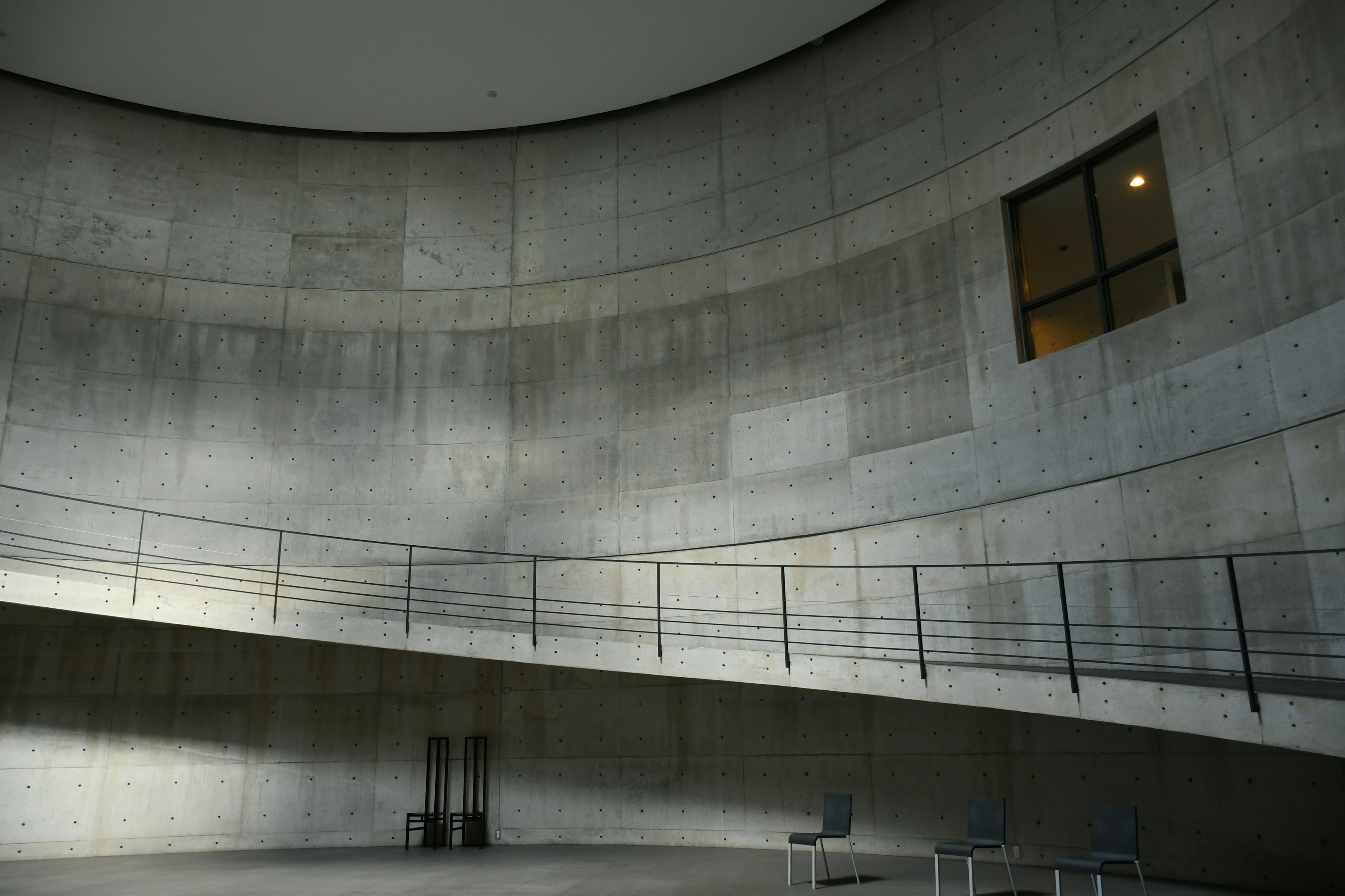 Intérieur en béton courbé avec un escalier et une fenêtre