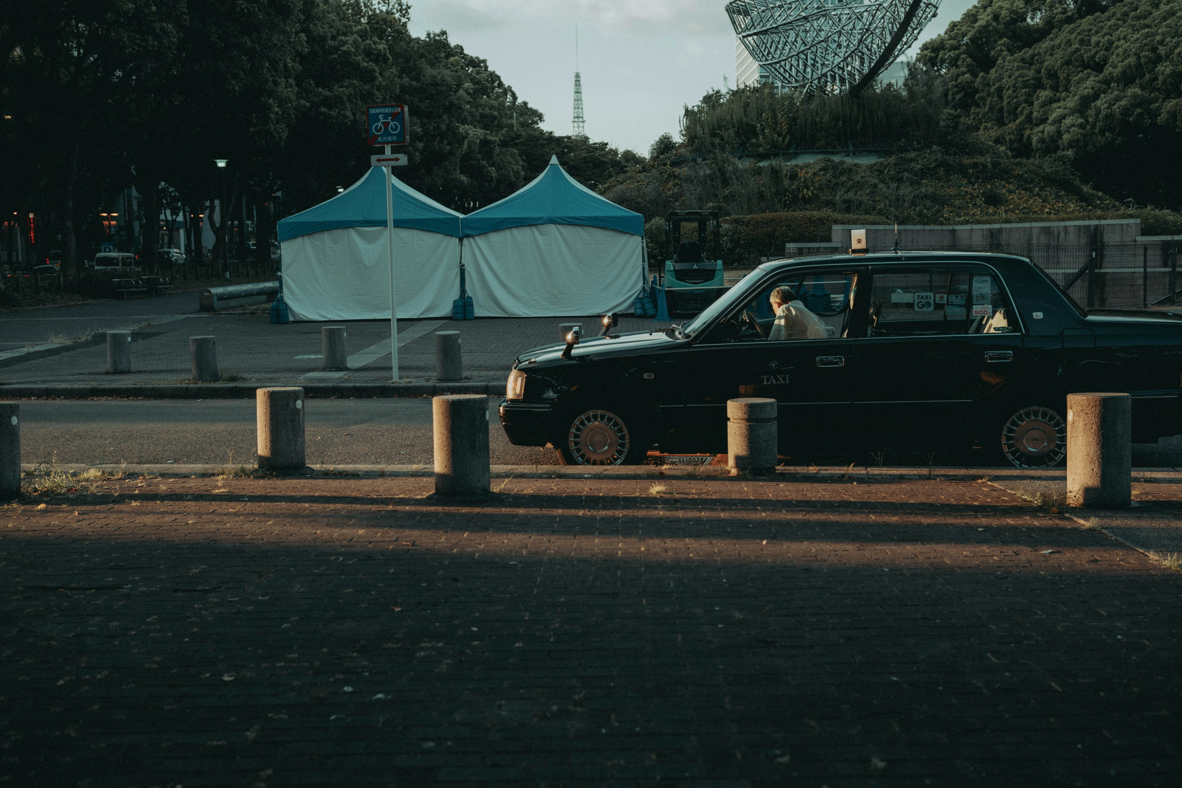 Taxi noir passant près de tentes bleues dans un environnement urbain