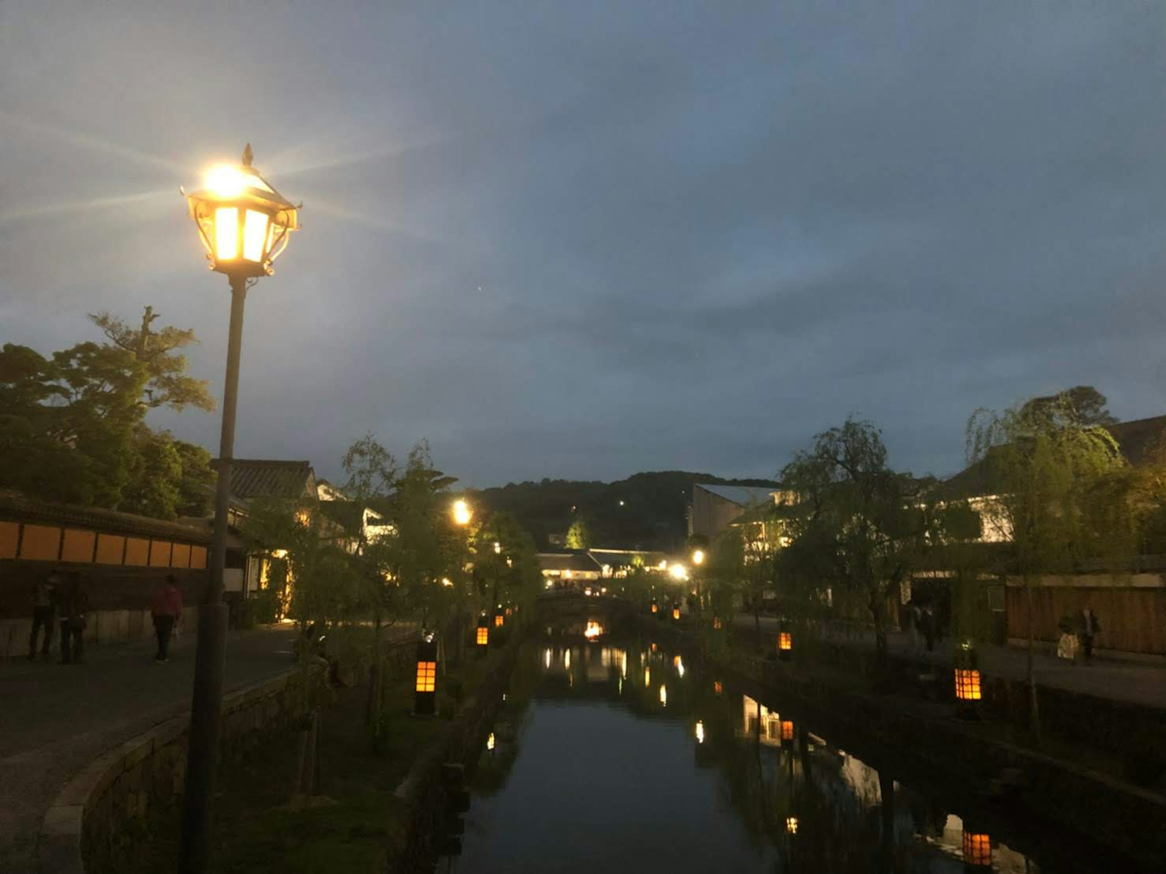 Scenic view of lanterns and streetlights along a riverside at dusk