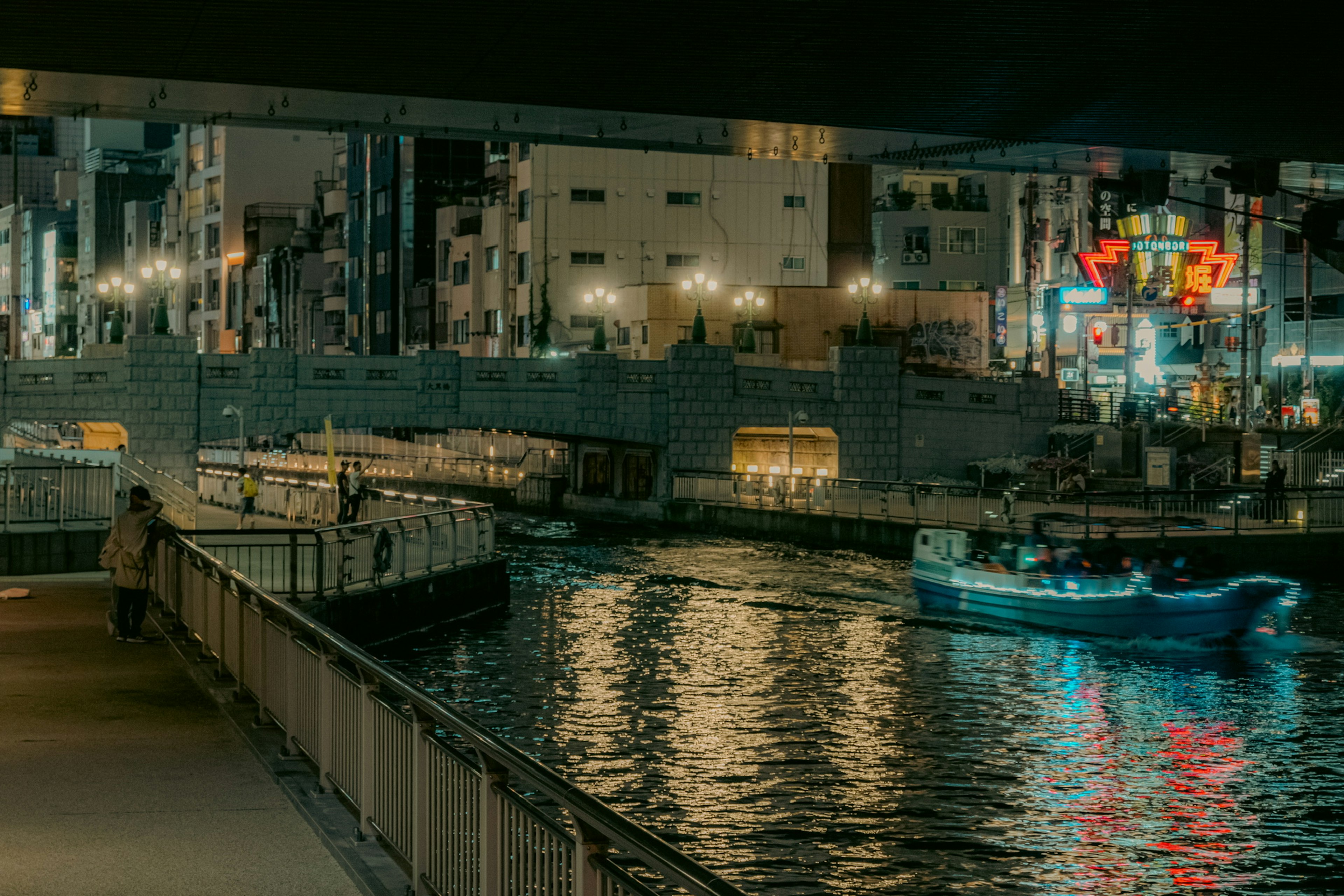 Night view of a river reflecting city lights with a boat on the calm water